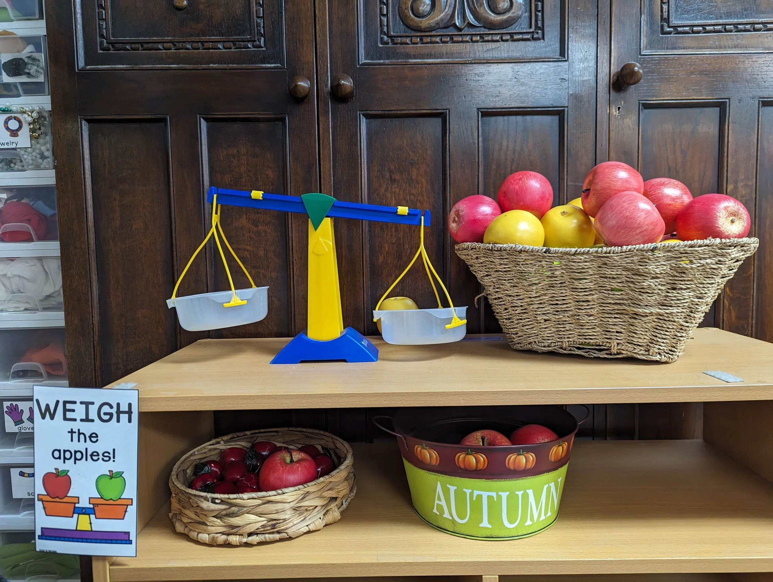 A balance scale next to a basket of apples.
