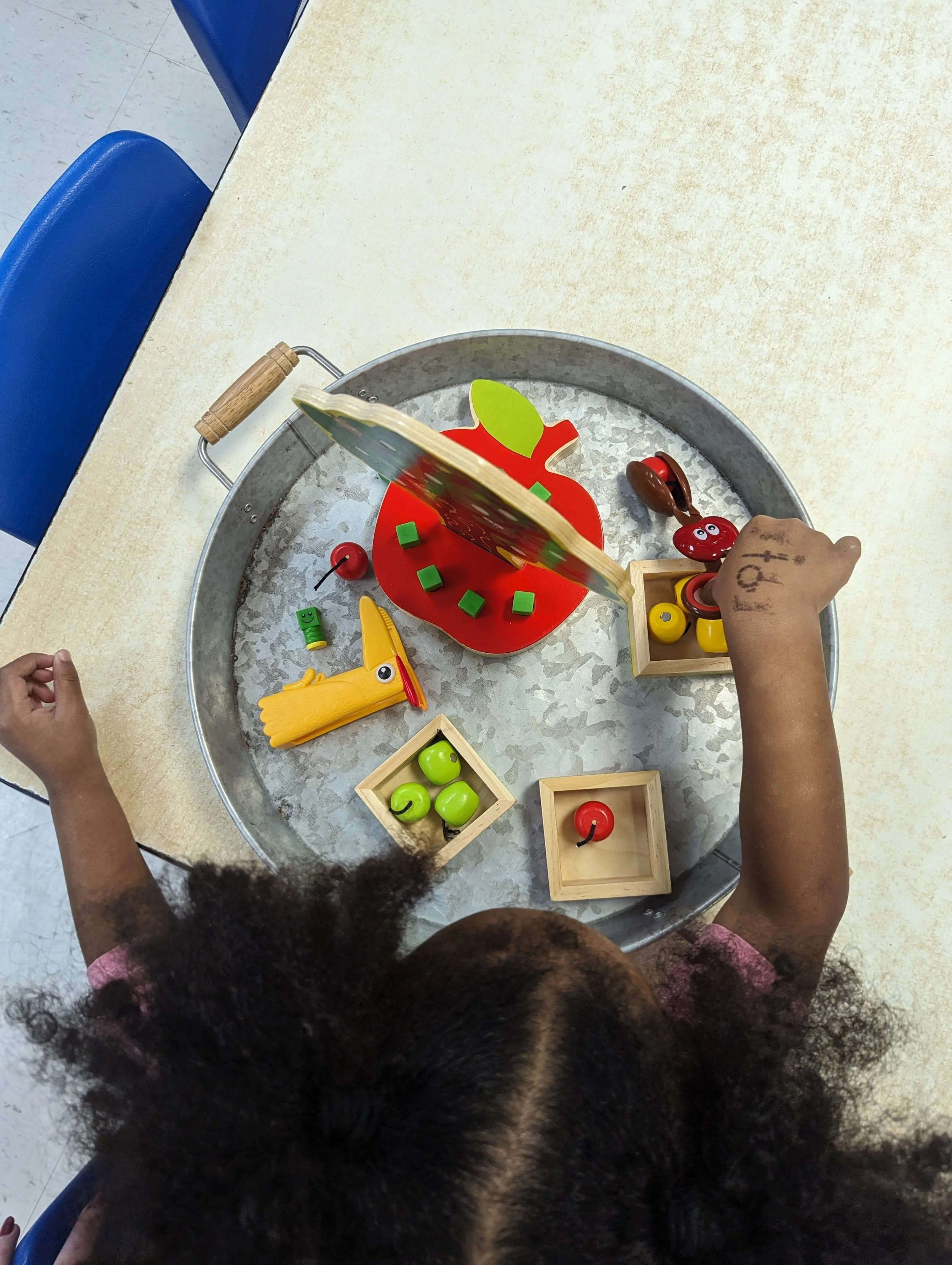 Child playing with wooden toy set, including red and green apples.