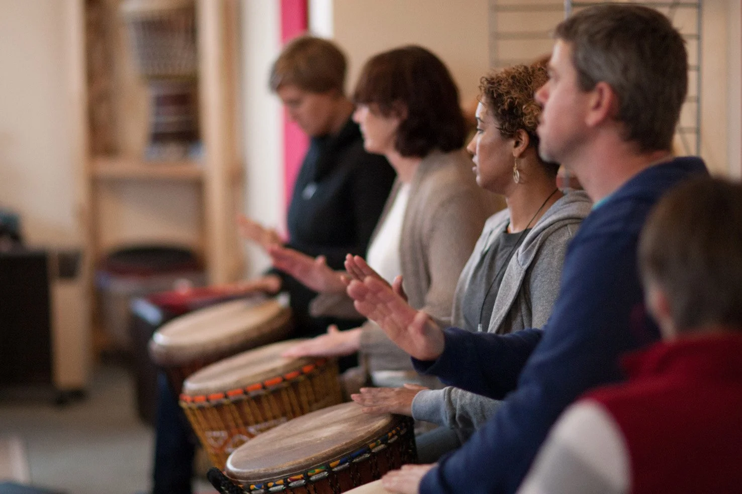 People drumming looking to the teacher