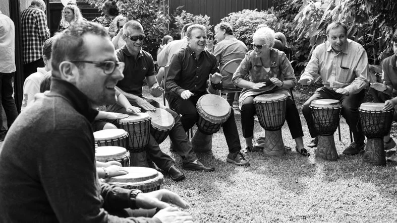 Group of people playing African drums laughing
