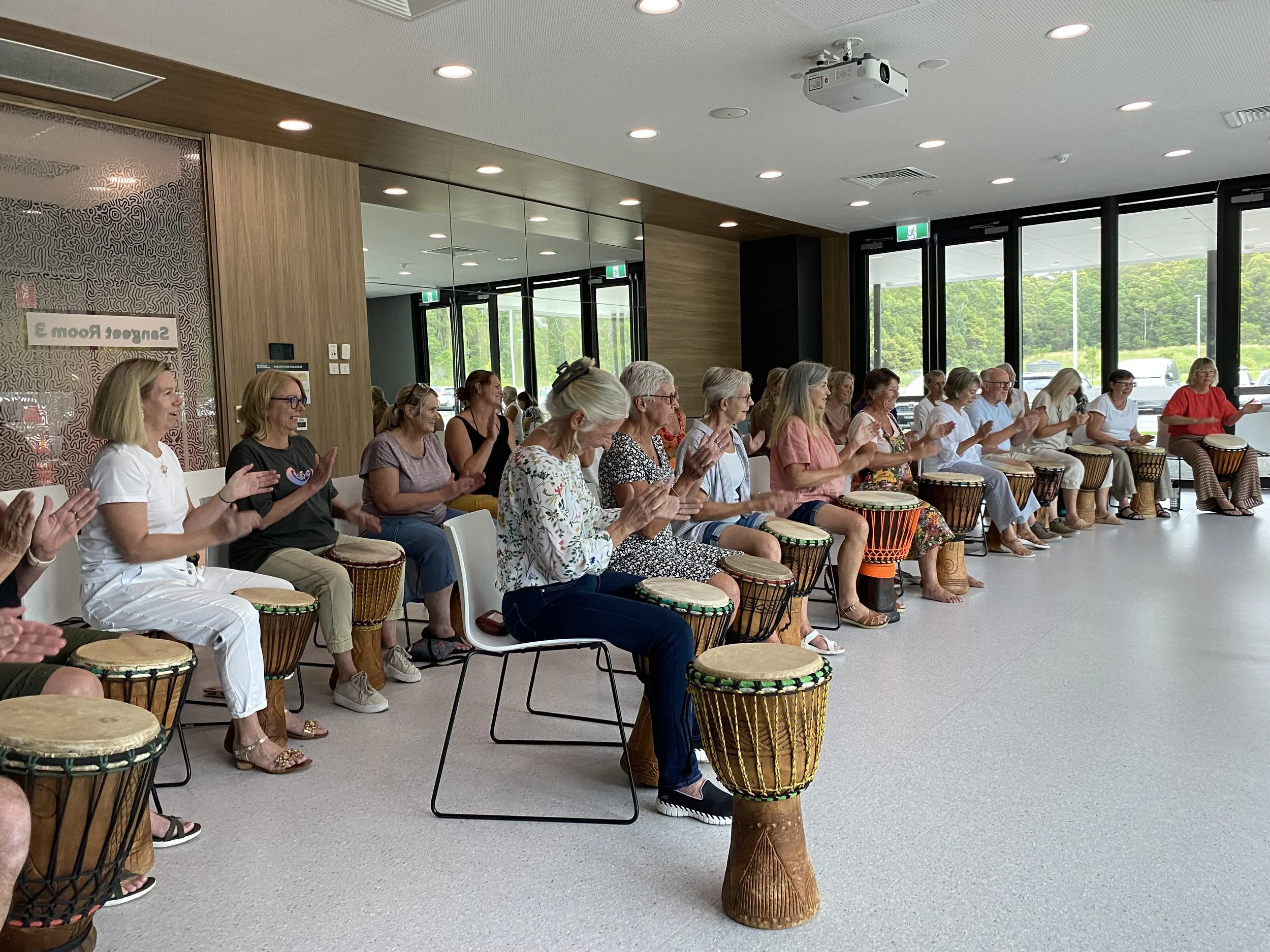 Women seated with drums and clapping
