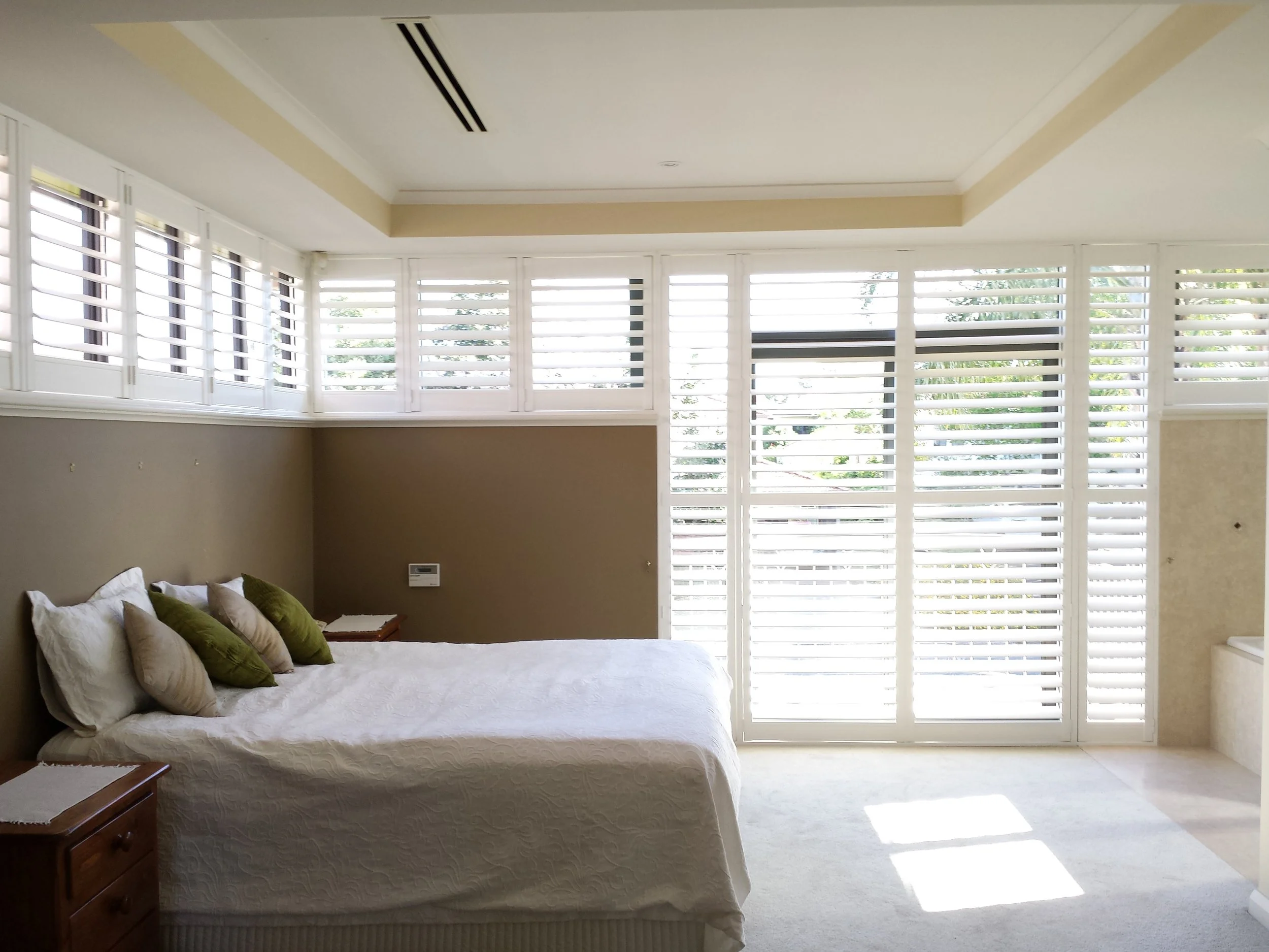 White PolySatin shutters on multiple windows in a master bedroom in Perth