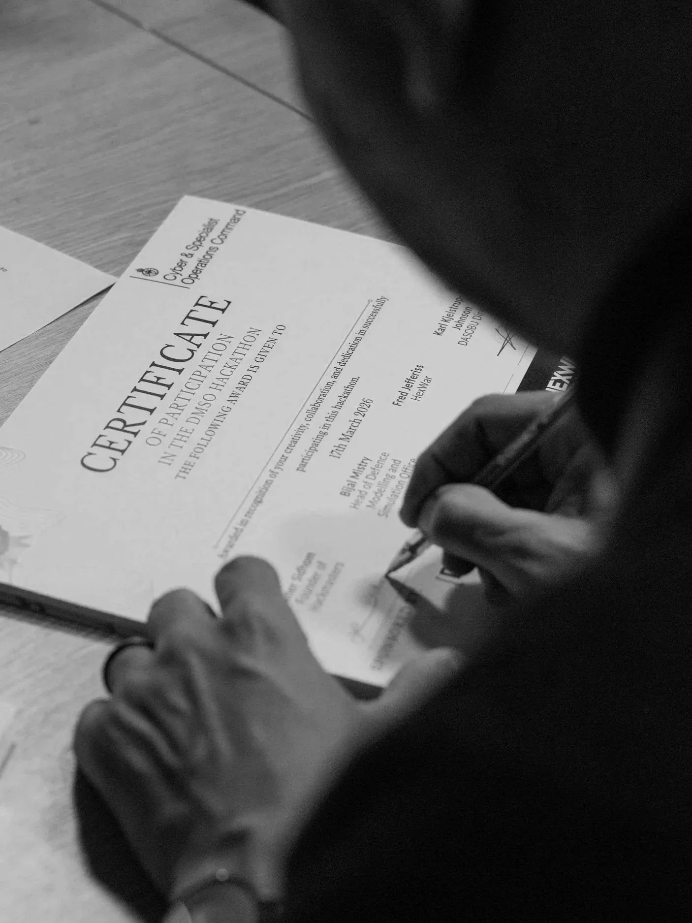 A person signing a certificate of participation on a wooden table.