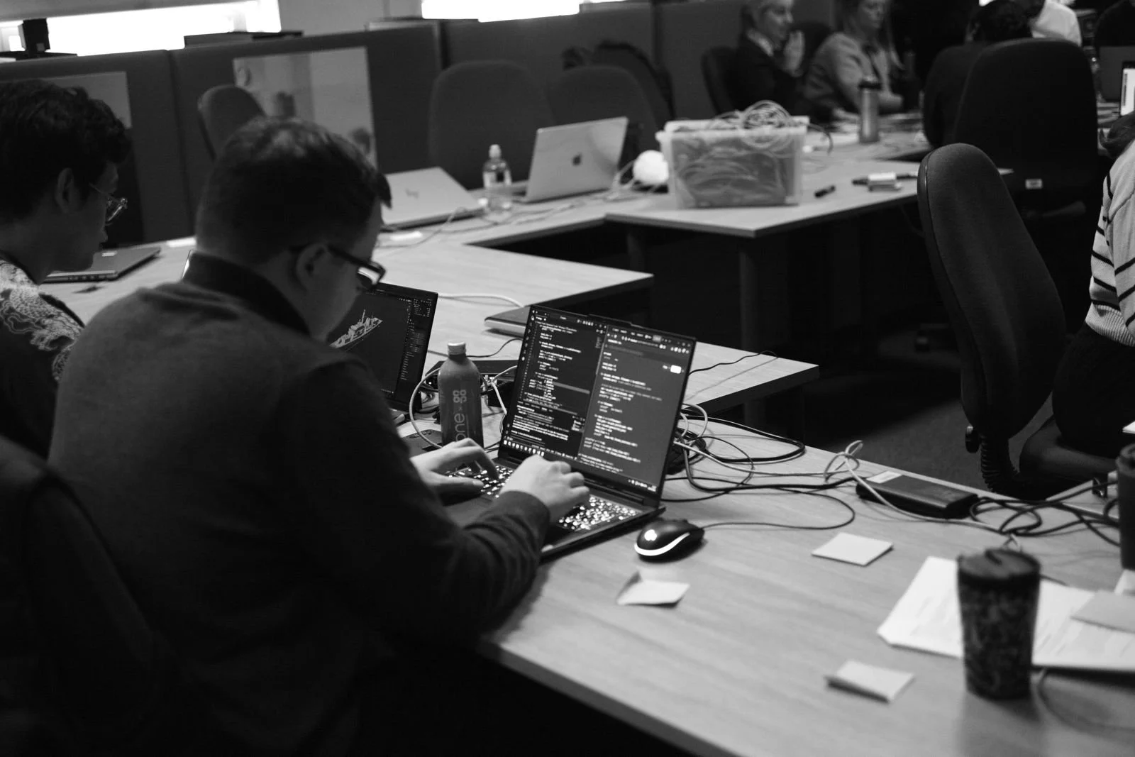 People working at a long conference table with laptops and papers.