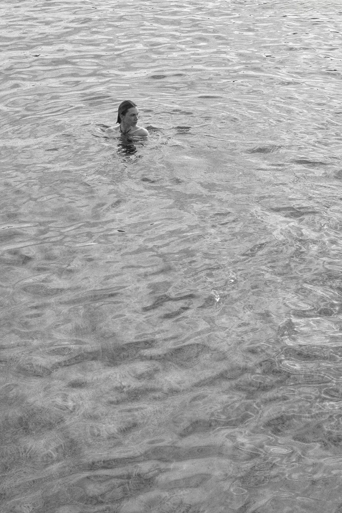 A woman swimming in the water with a serene expression.