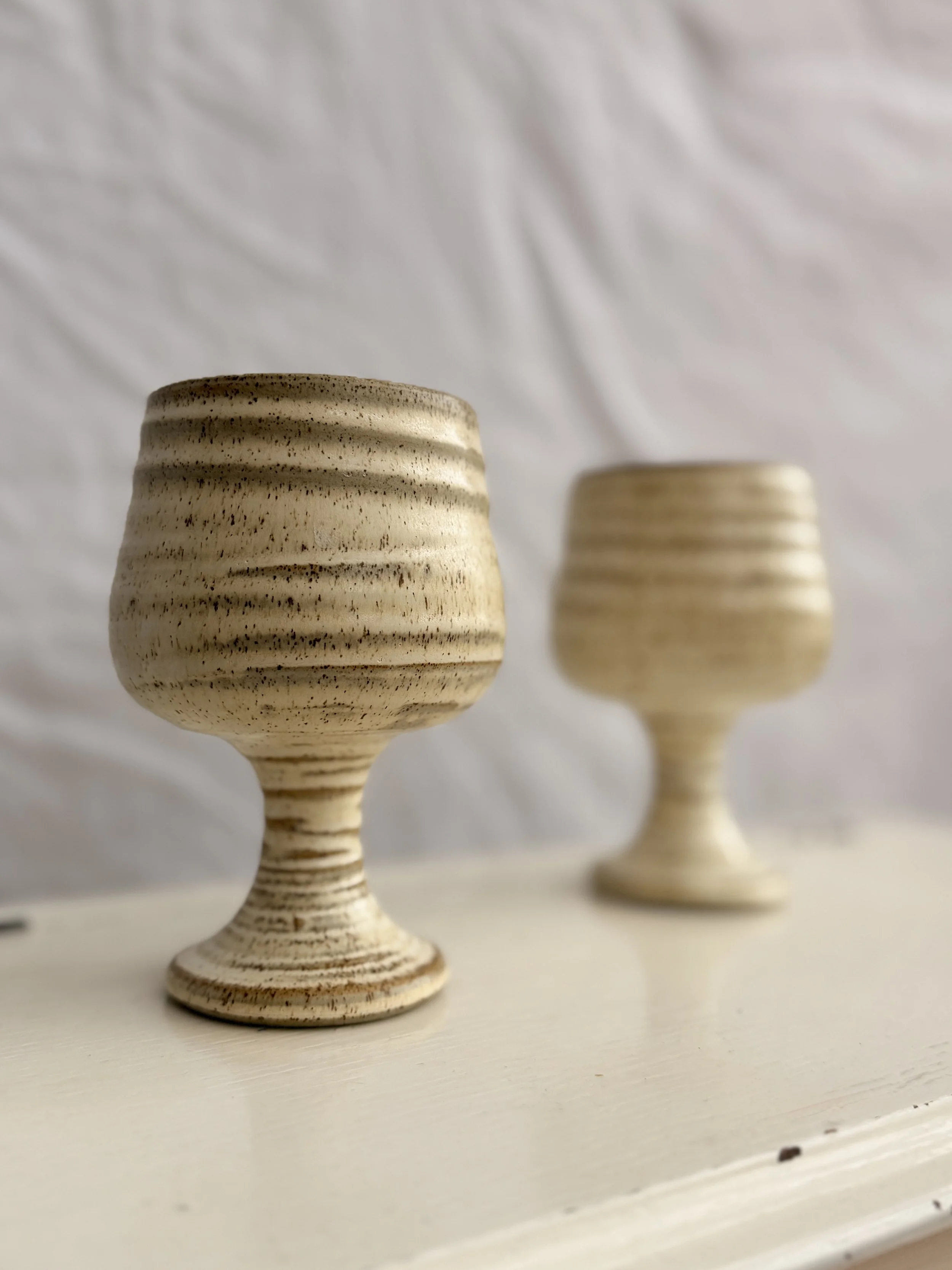 Detail shot showing the speckled oatmeal glaze and earthy texture of the pottery.