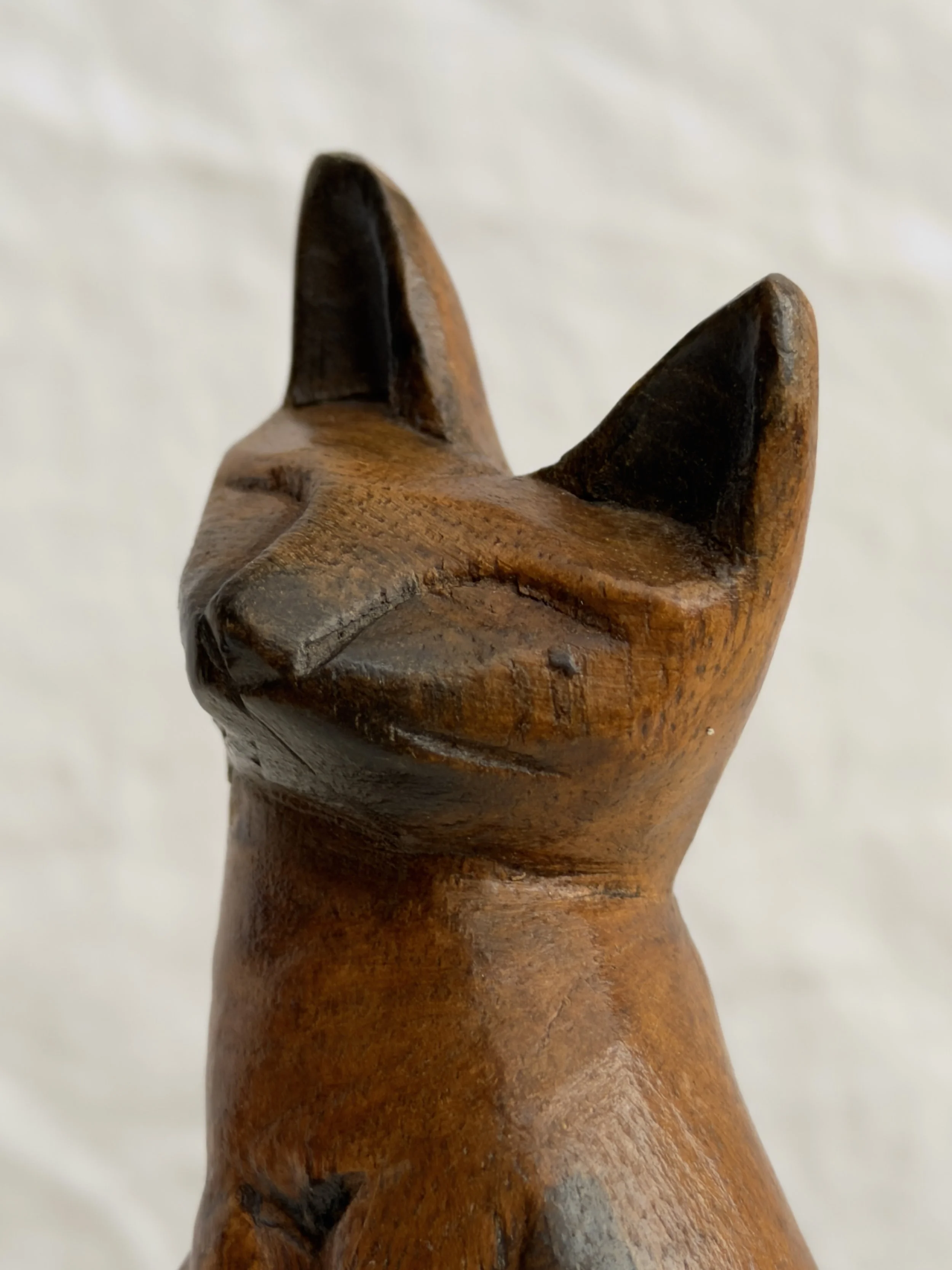 Close-up of a carved wooden cat showing the handcrafted texture and warm honey-toned wood.