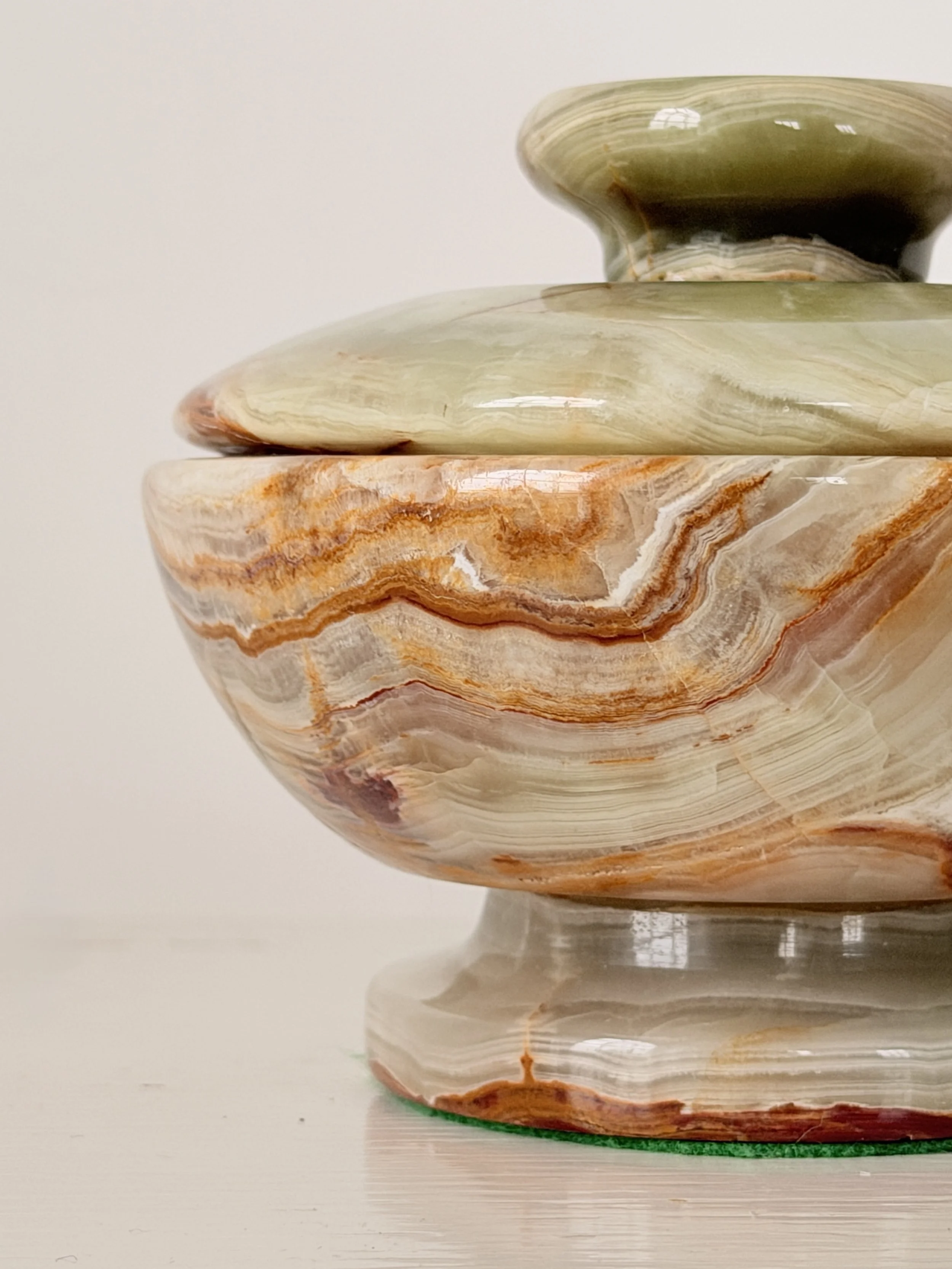 Close-up macro shot of the natural mineral bands and polished finish of a green onyx decorative dish.