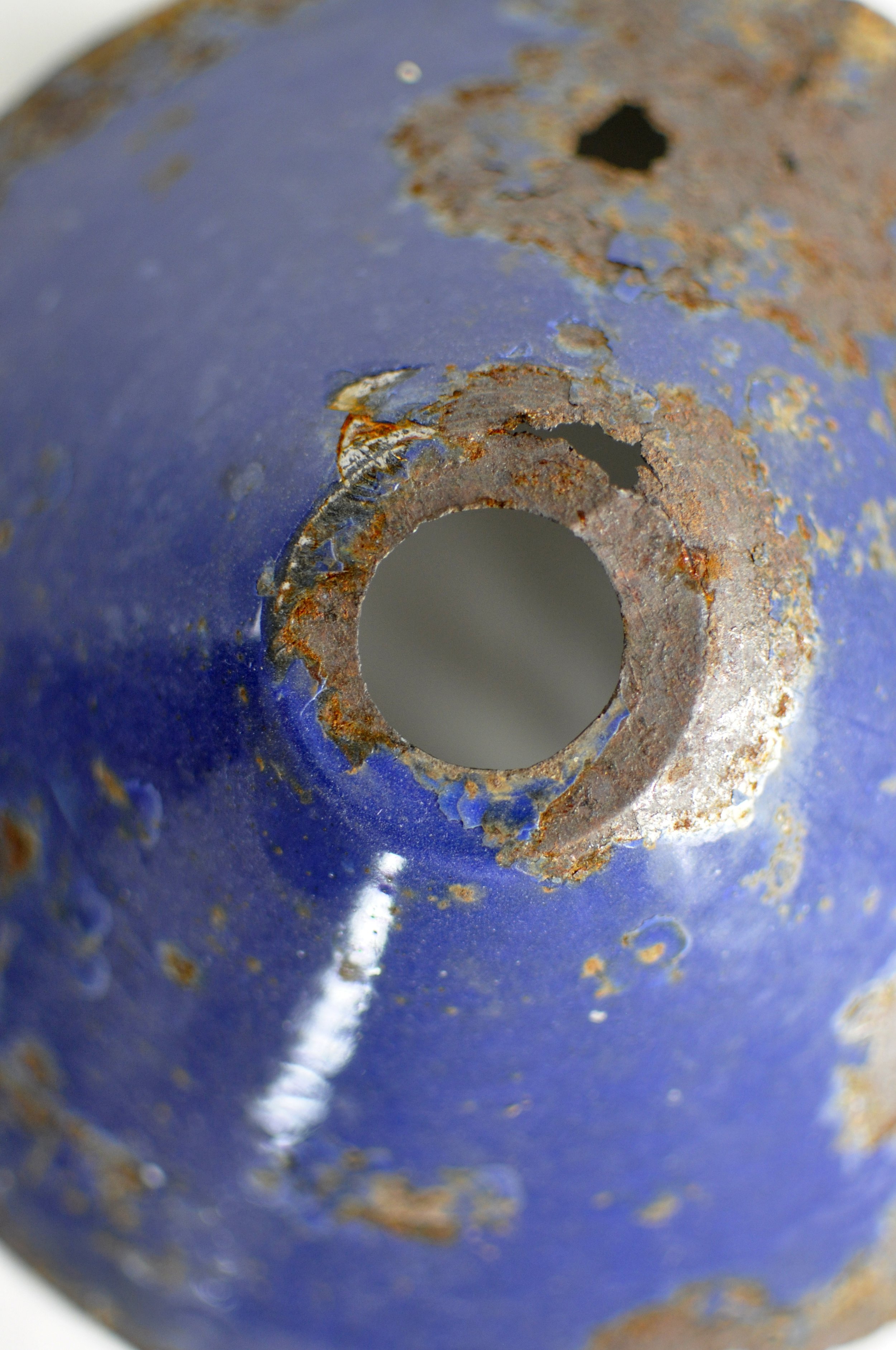Close-up of authentic rust and enamel wear on a 1930s blue lampshade.