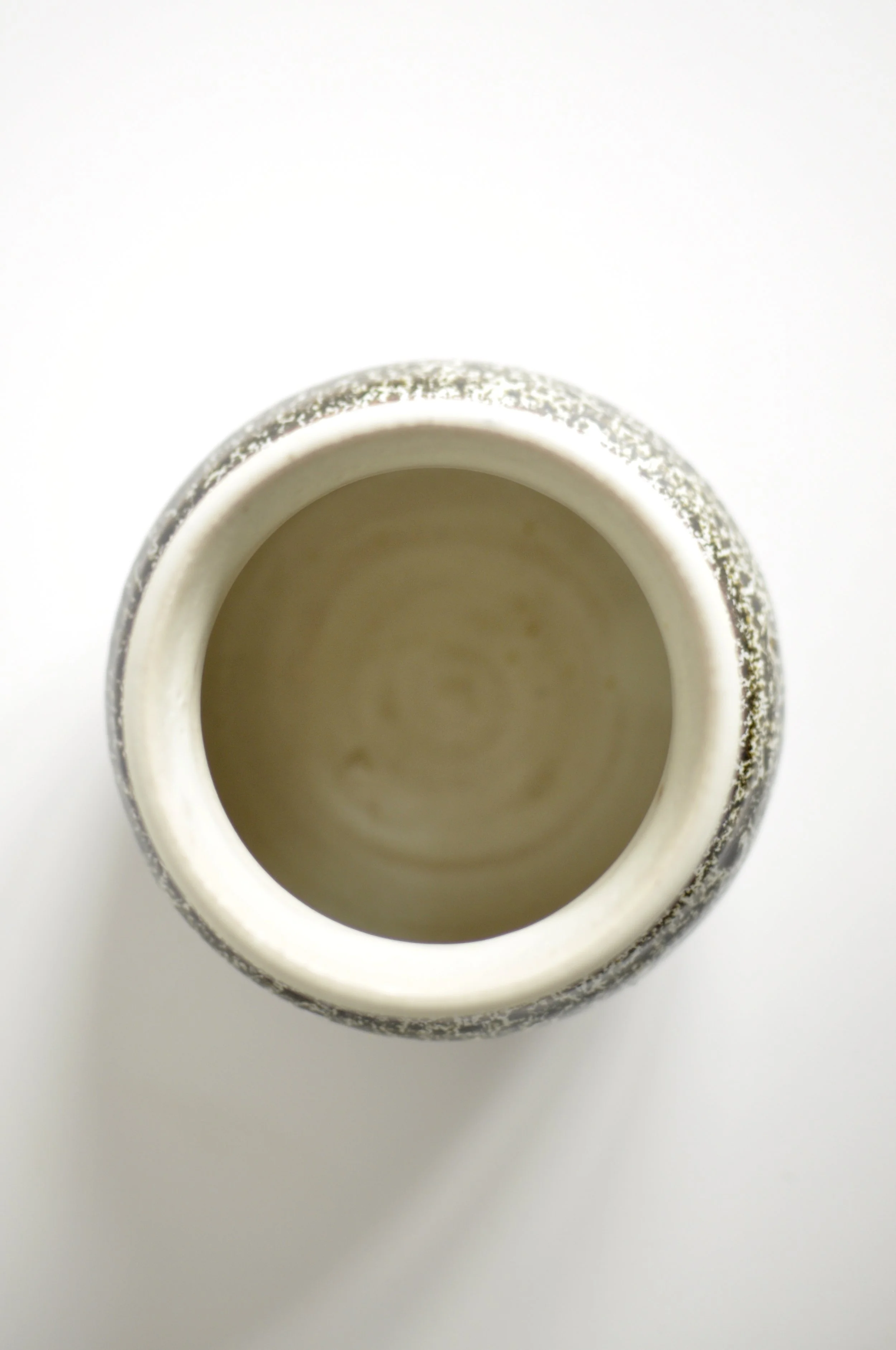 Off-white interior and hand-thrown rim of a Backwater Pottery vase.