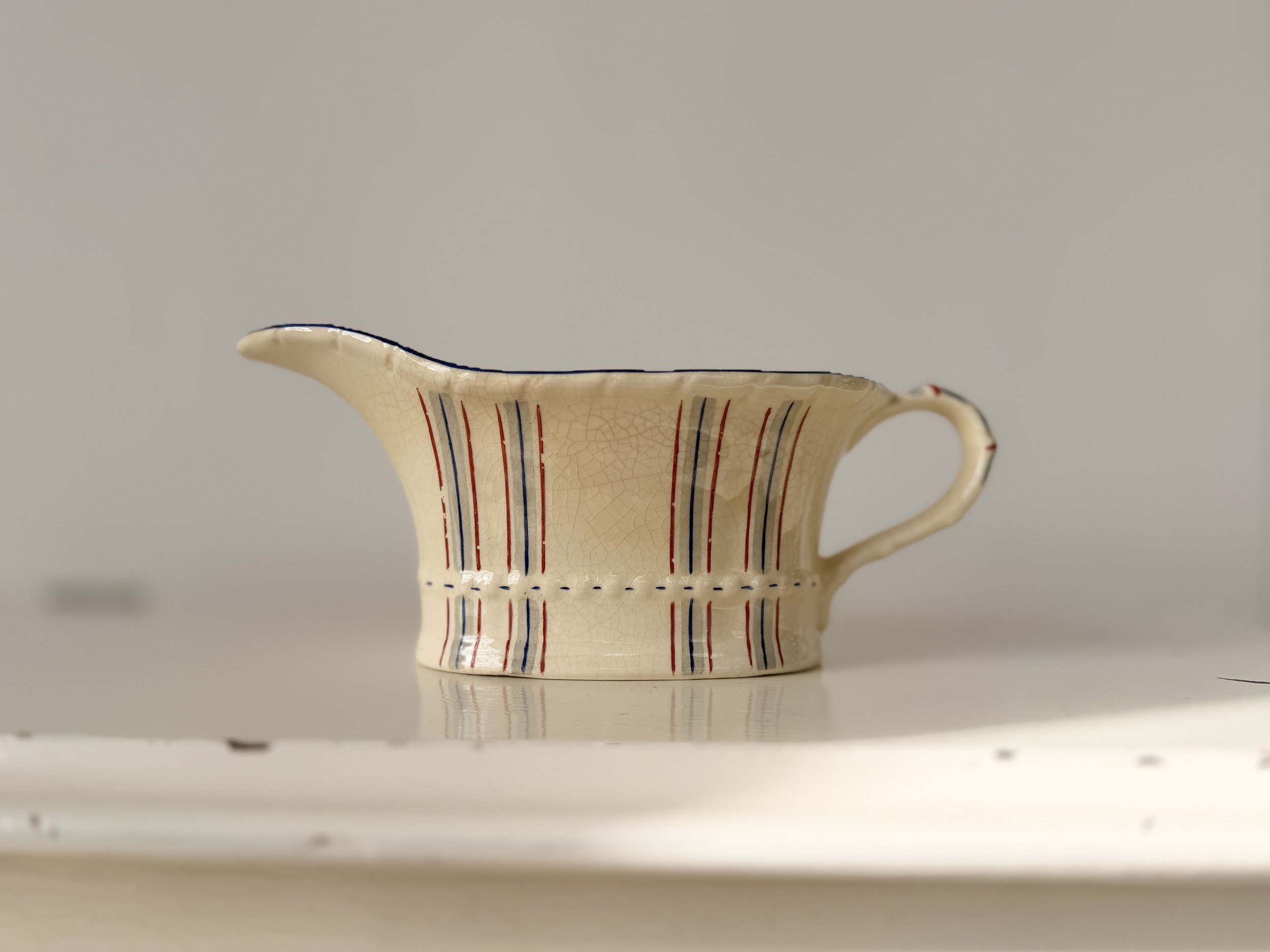 A "perfectly imperfect" vintage sauce boat with visible glaze crazing, highlighting its 90-year history.