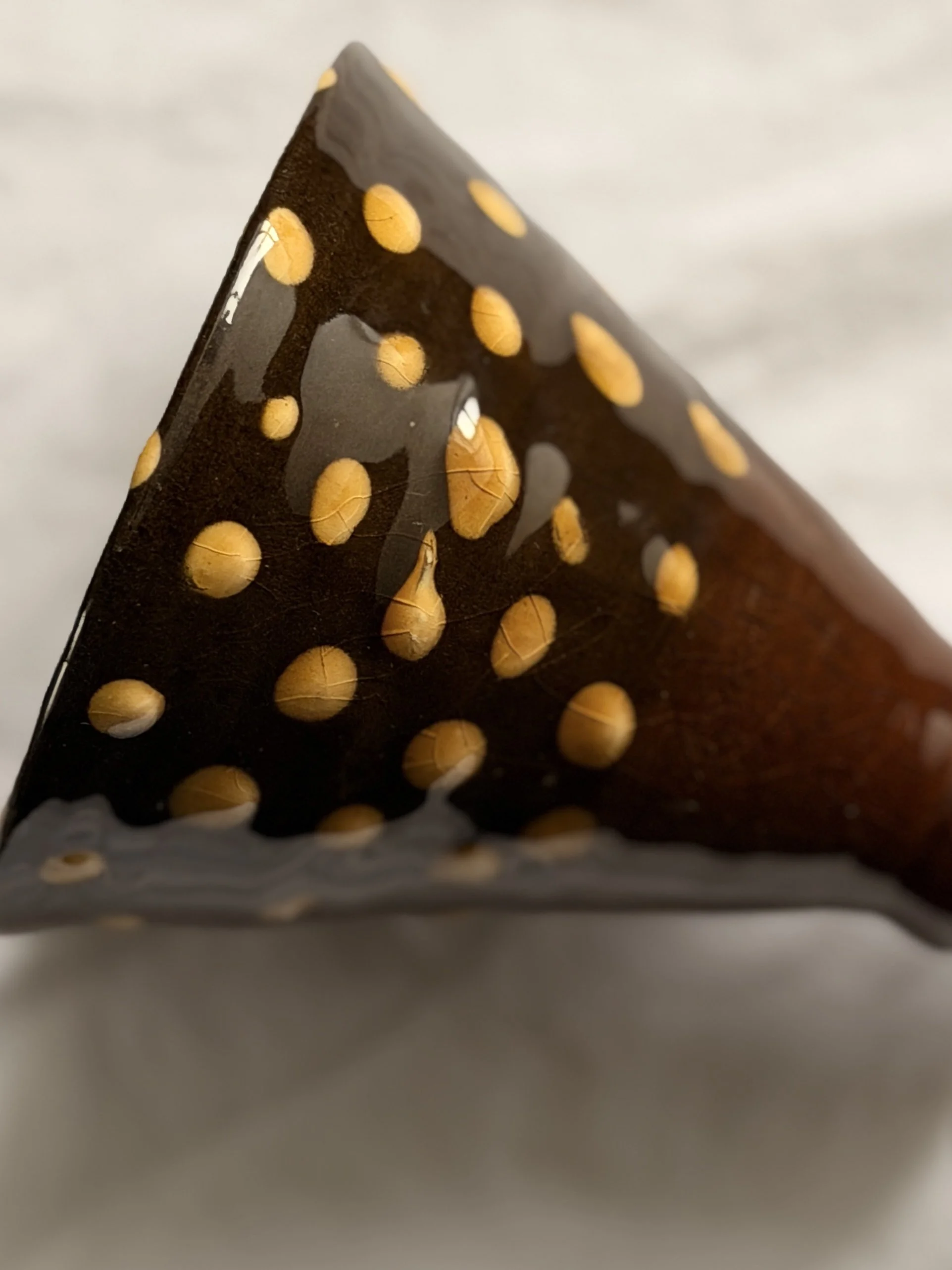 A rustic stoneware pedestal bowl featuring a unique hand-thrown shape and decorative dotted pattern.