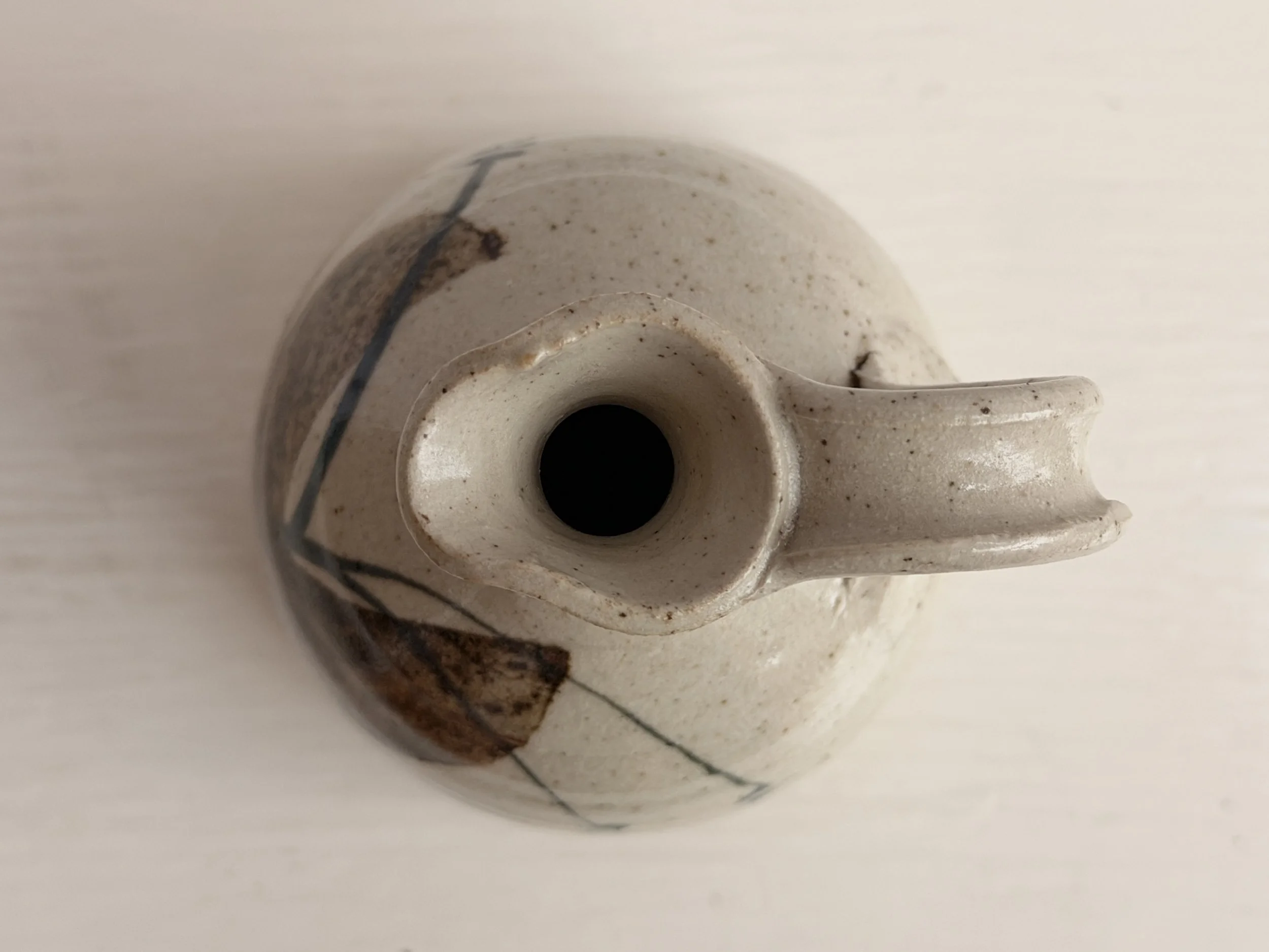 Top-down view of the pouring lip and interior of a handmade stoneware studio pottery jug.