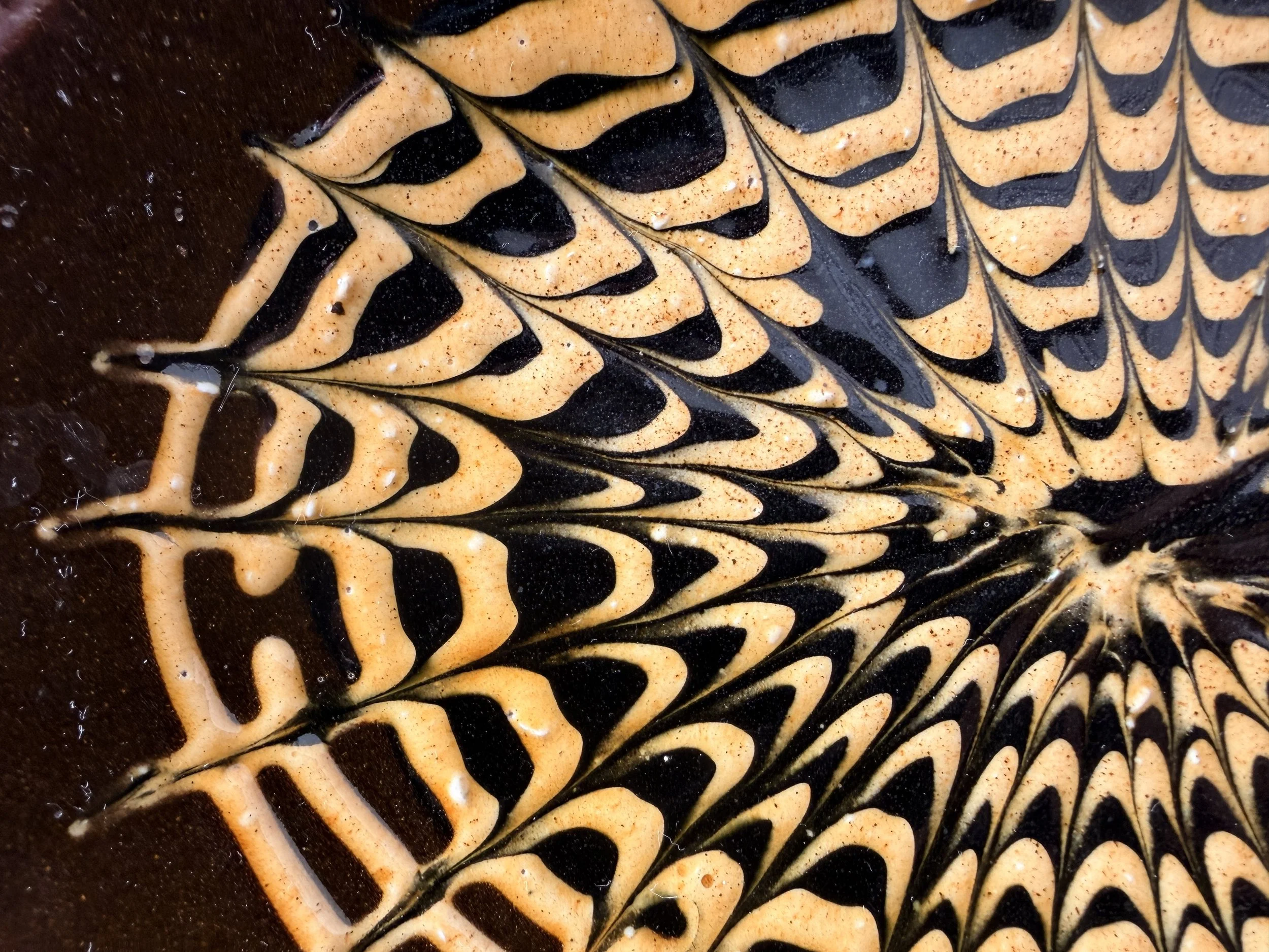 Close-up of kiln-fired glaze variations on a hand-thrown ceramic serving piece.