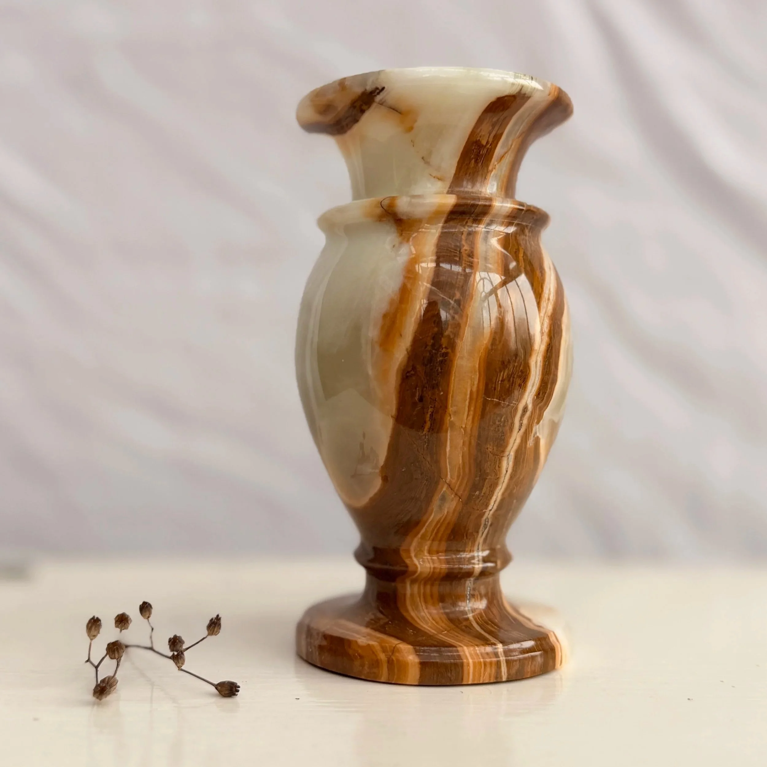 A heavy, vintage banded onyx vase featuring natural swirls of cream, honey, and amber stone.