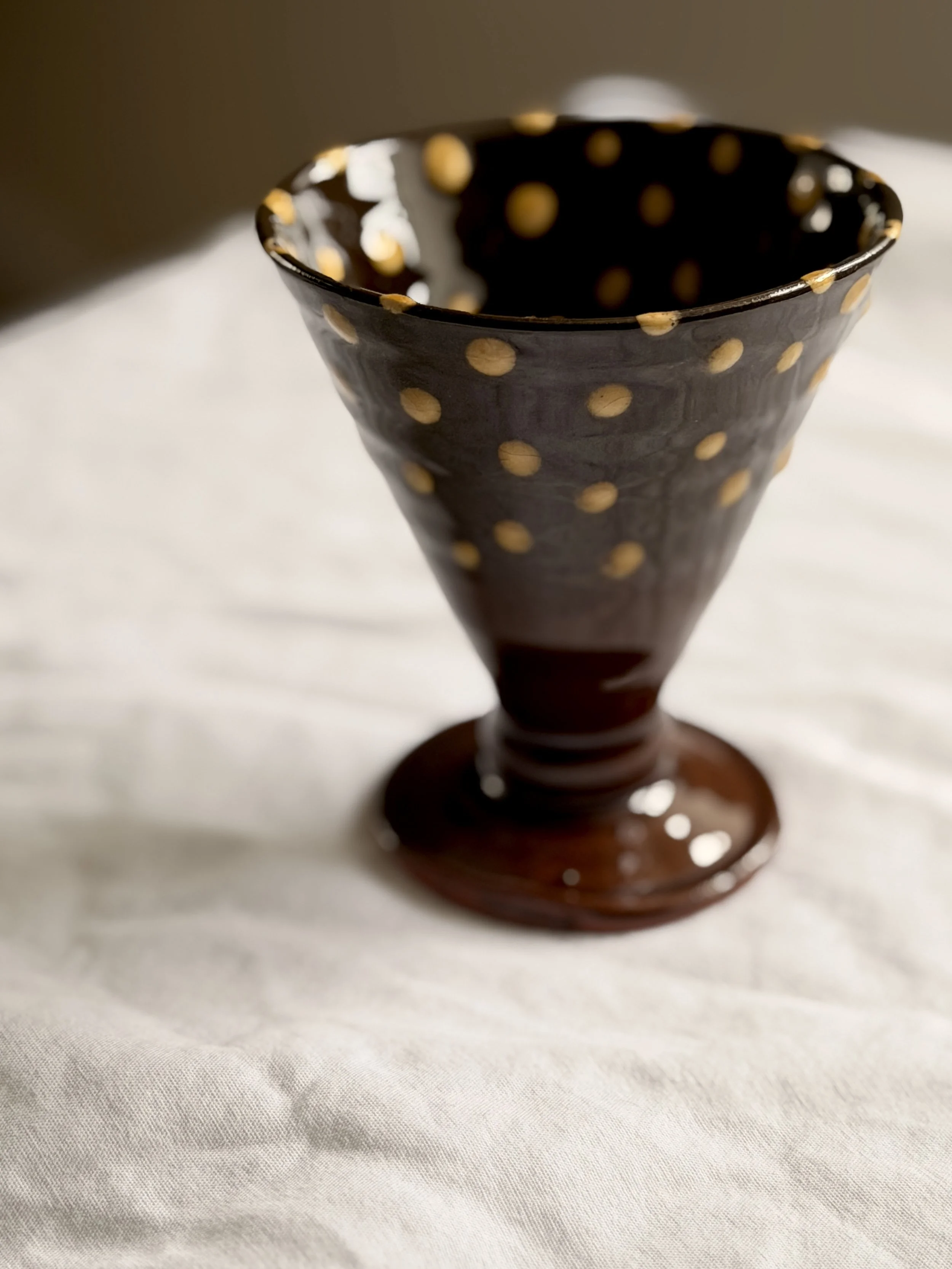 Close-up of a studio pottery chalice showing the artisan texture and earthy glazed finish.