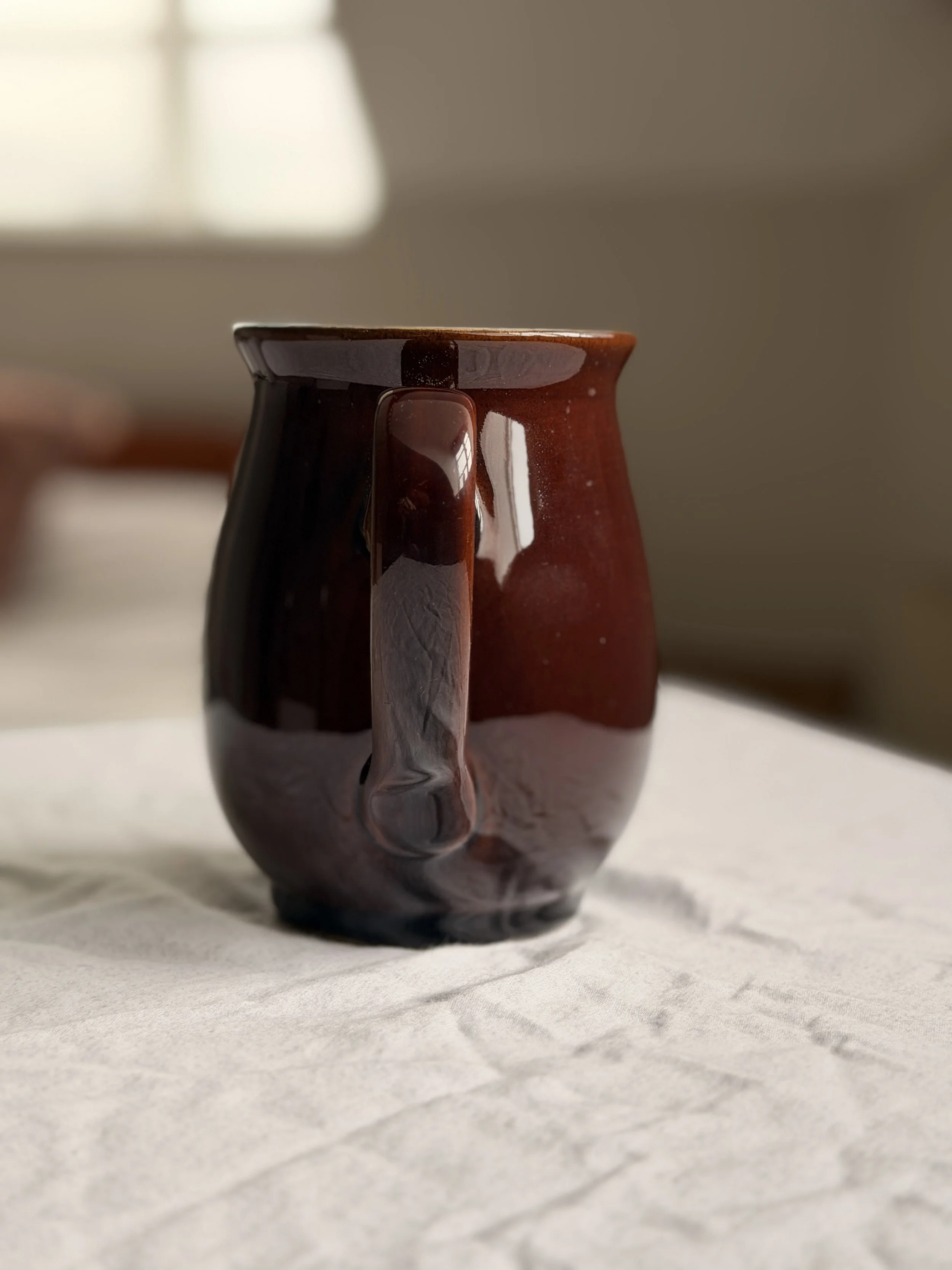 Mid-century modern Denby pitcher in Homestead Brown showing the elegant curved handle and flared rim design by Donald Gilbert.