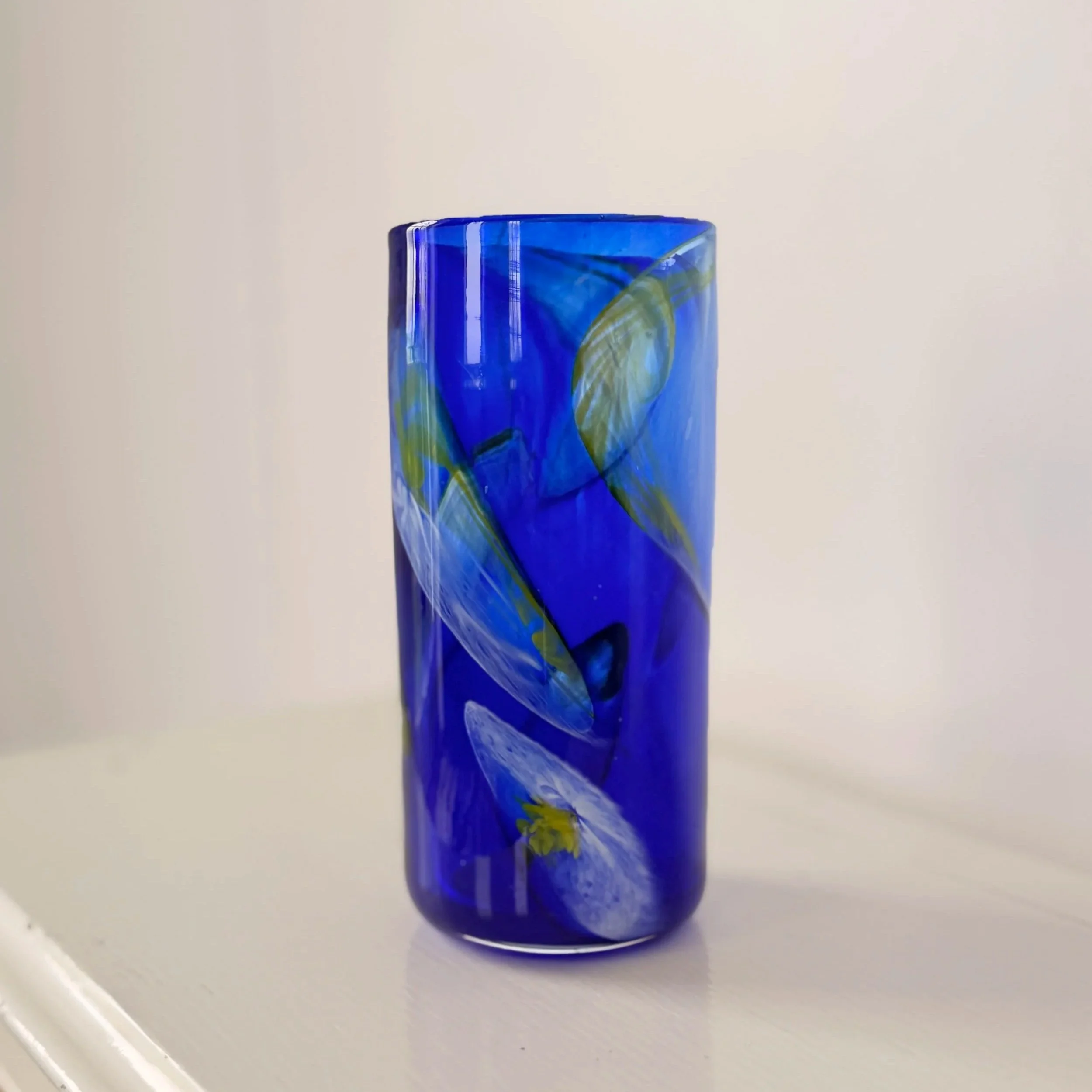 A striking vintage cobalt blue studio glass vase with a tall, slender neck and rounded base.
