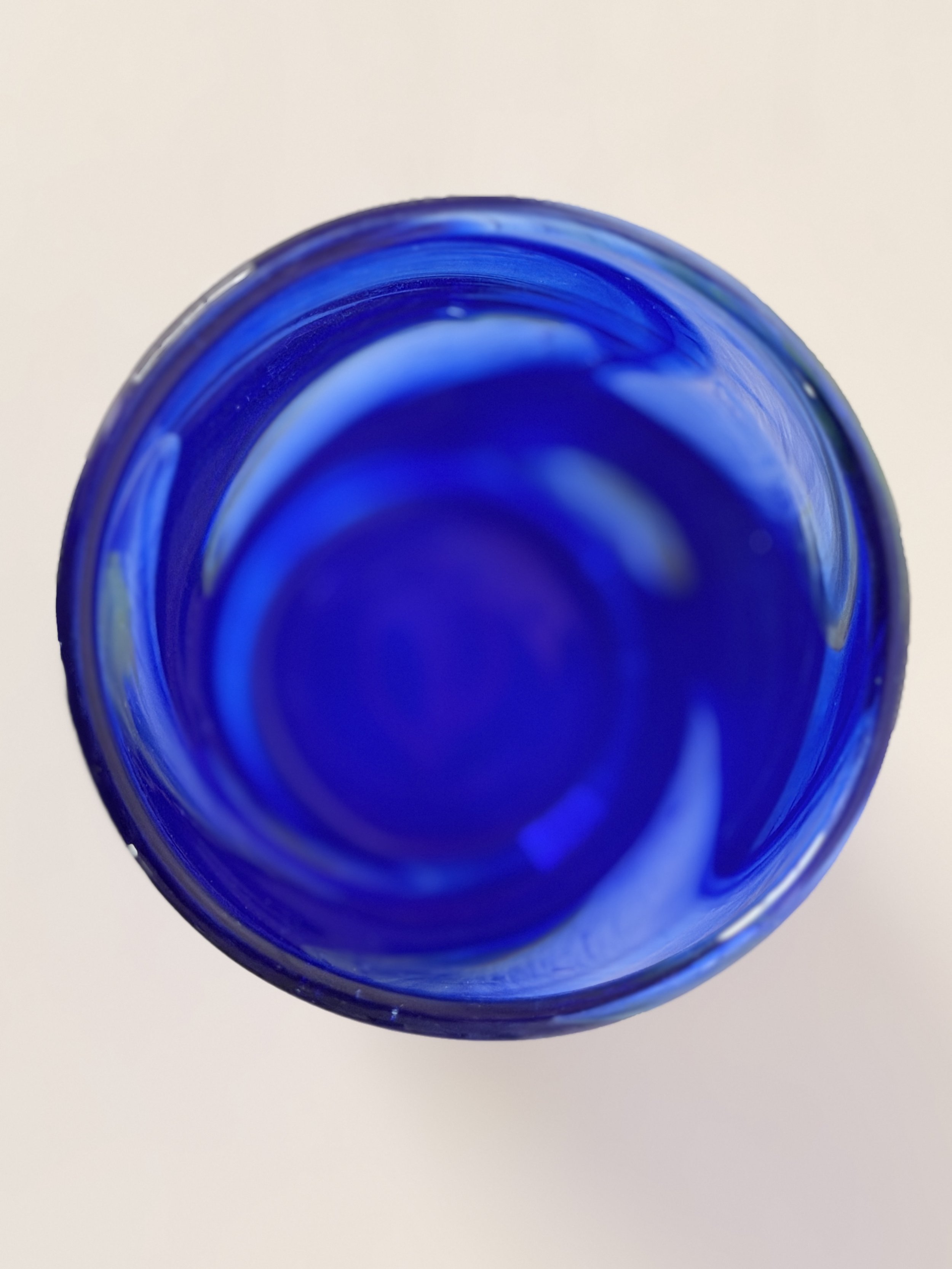 A high-angle shot showing the smooth, polished rim of the hand-crafted blue glass vase