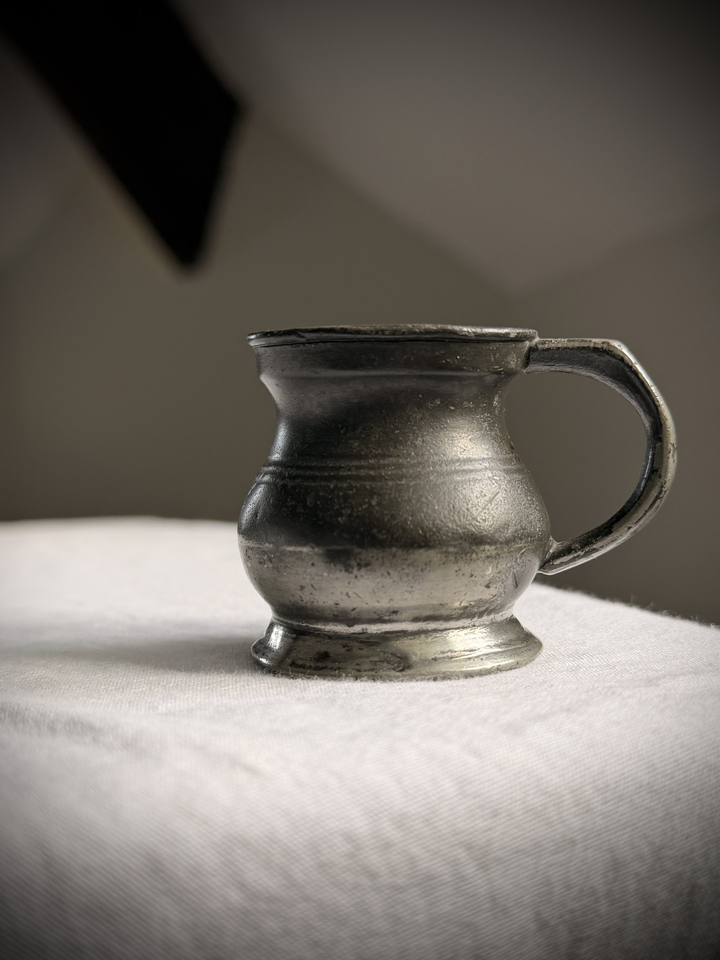 Antique 19th-century pewter spirit measure with a dark patina