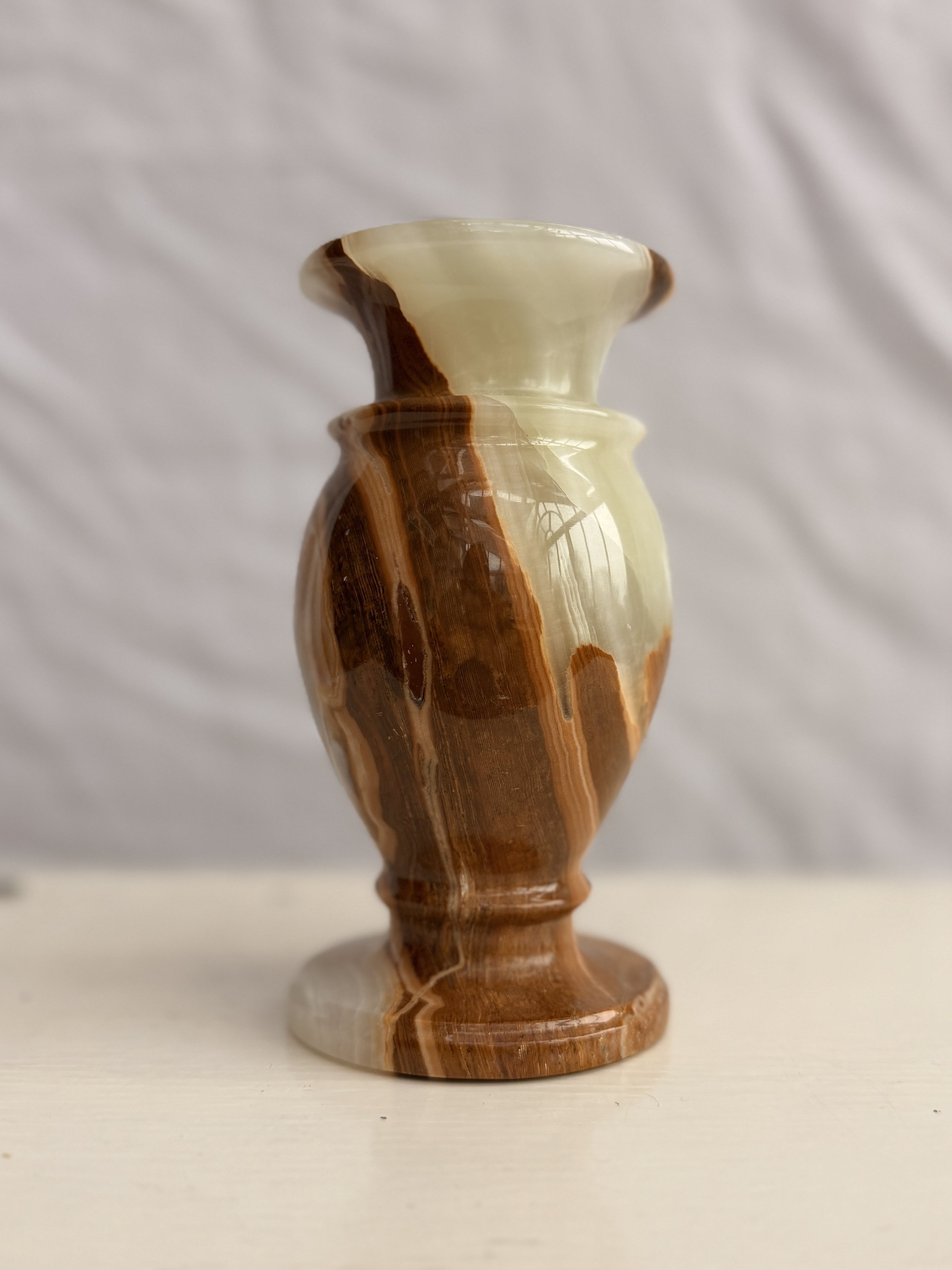 A heavy, vintage banded onyx vase featuring natural swirls of cream, honey, and amber stone.