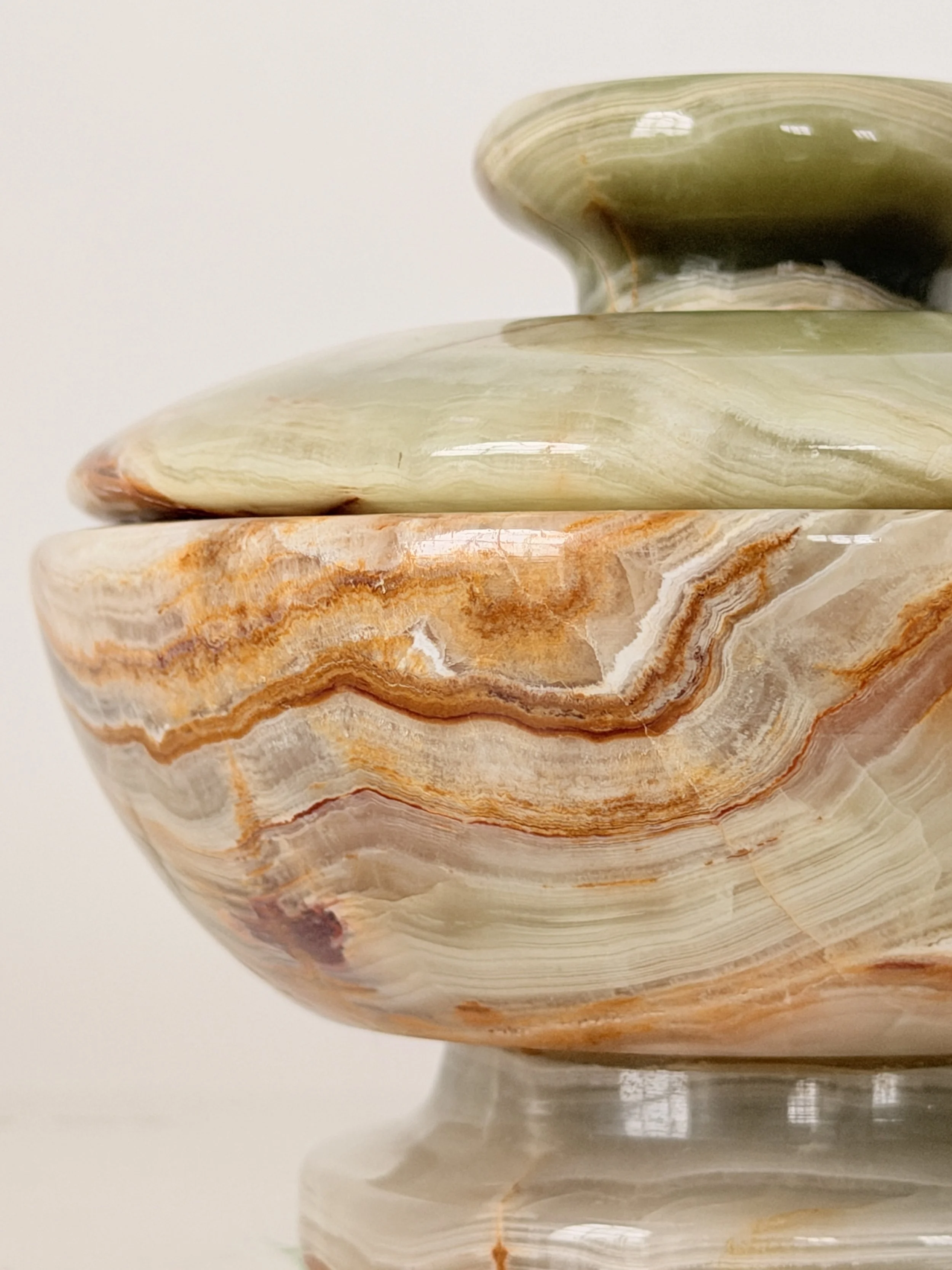 Close-up macro shot of the natural mineral bands and polished finish of a green onyx decorative dish.