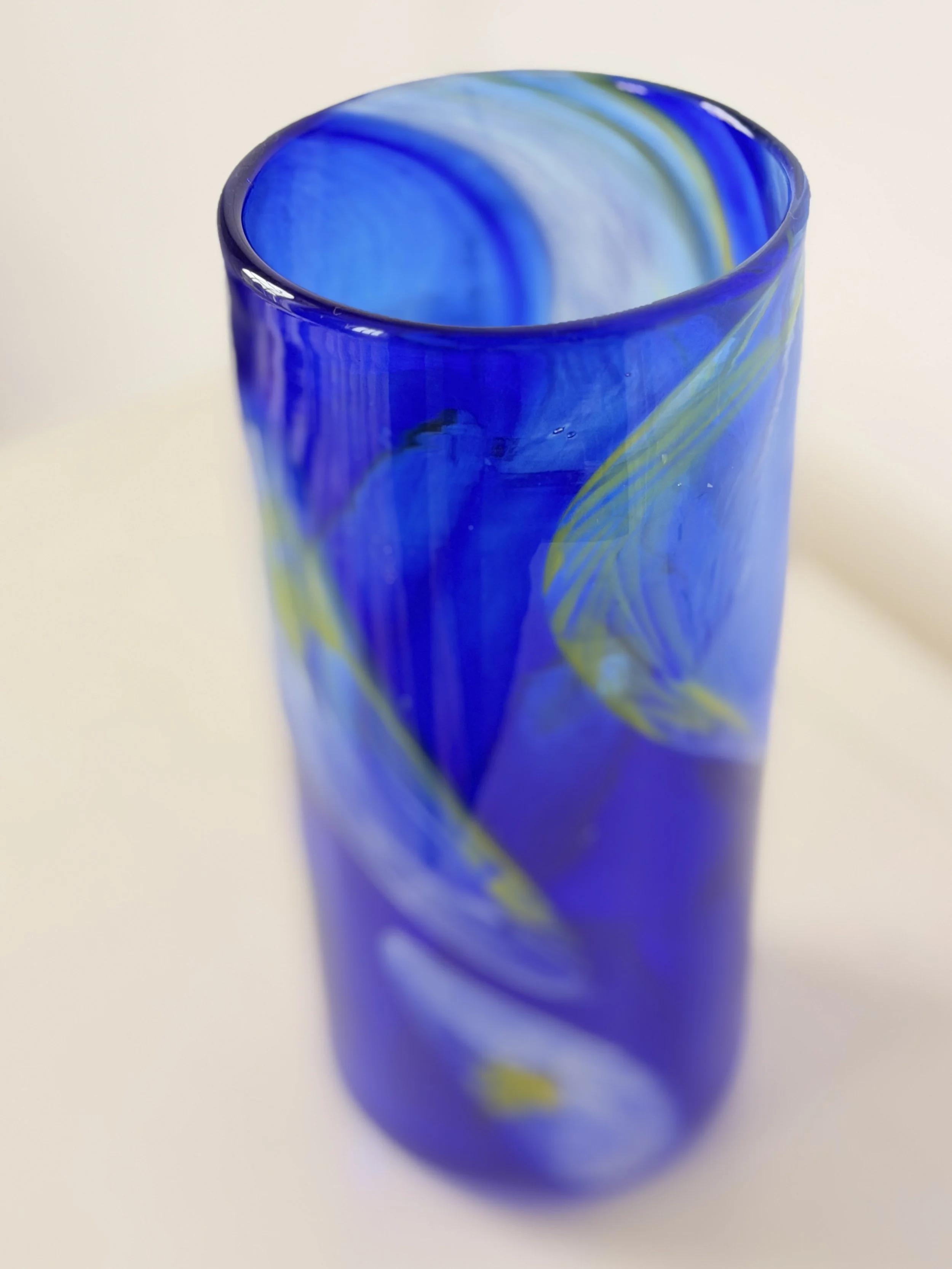 A high-angle shot showing the smooth, polished rim of the hand-crafted blue glass vase