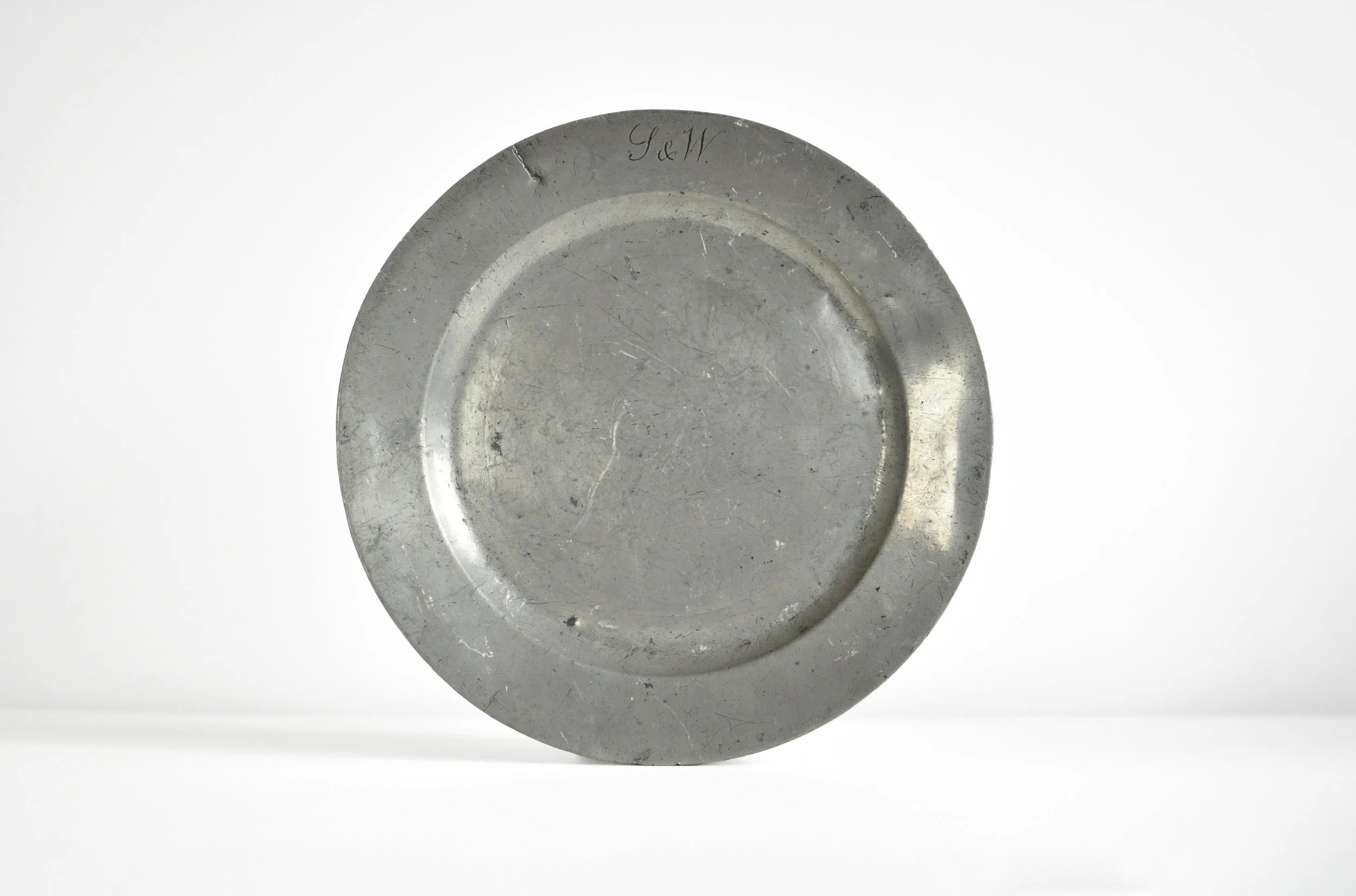 Shop this authentic 18th-century London pewter plate. Featuring a rare Crowned X mark and S&W monogram, this heavyweight sadware piece is perfect for antique collectors.
