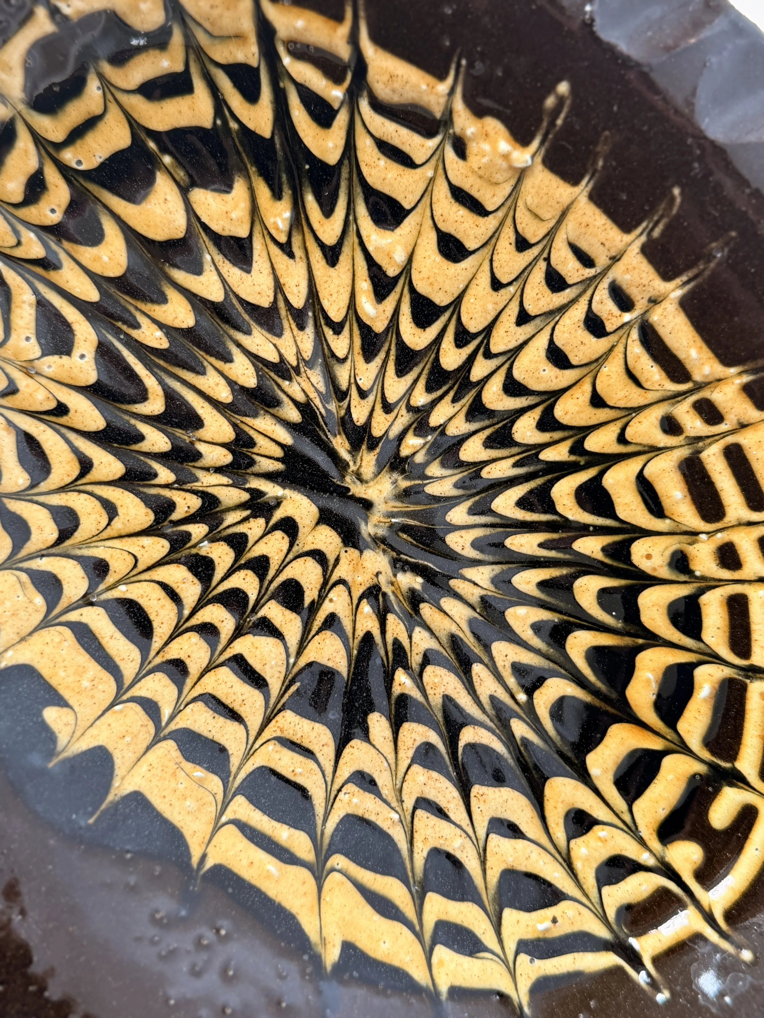 Close-up of kiln-fired glaze variations on a hand-thrown ceramic serving piece.