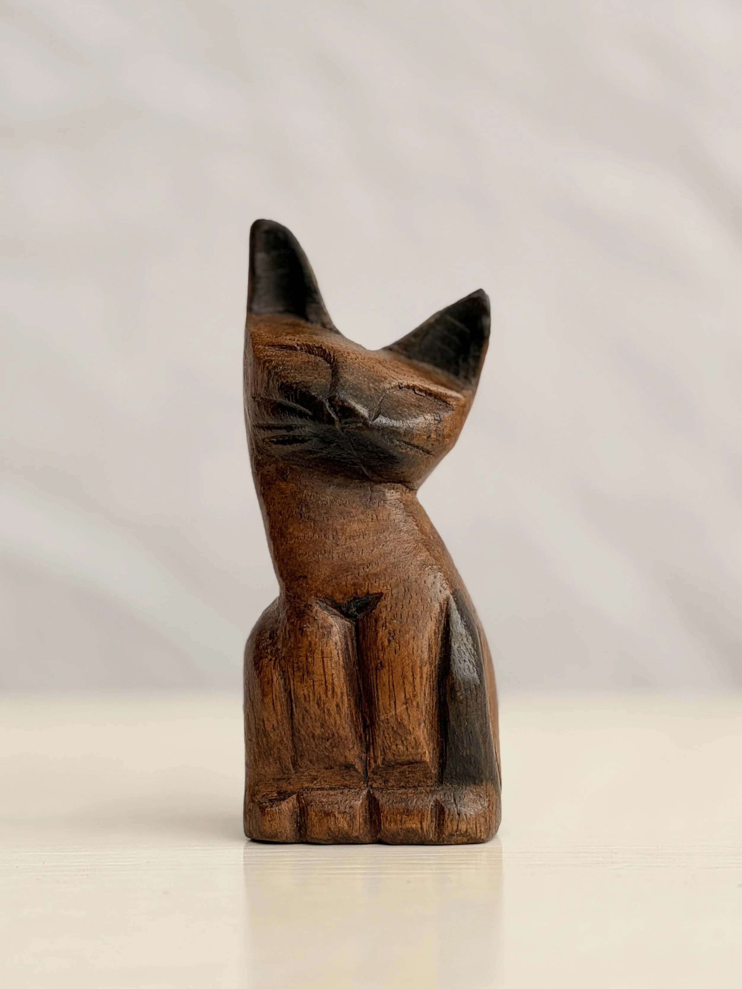 A hand-carved wooden cat figurine with a smooth, vintage-style finish and visible wood grain.