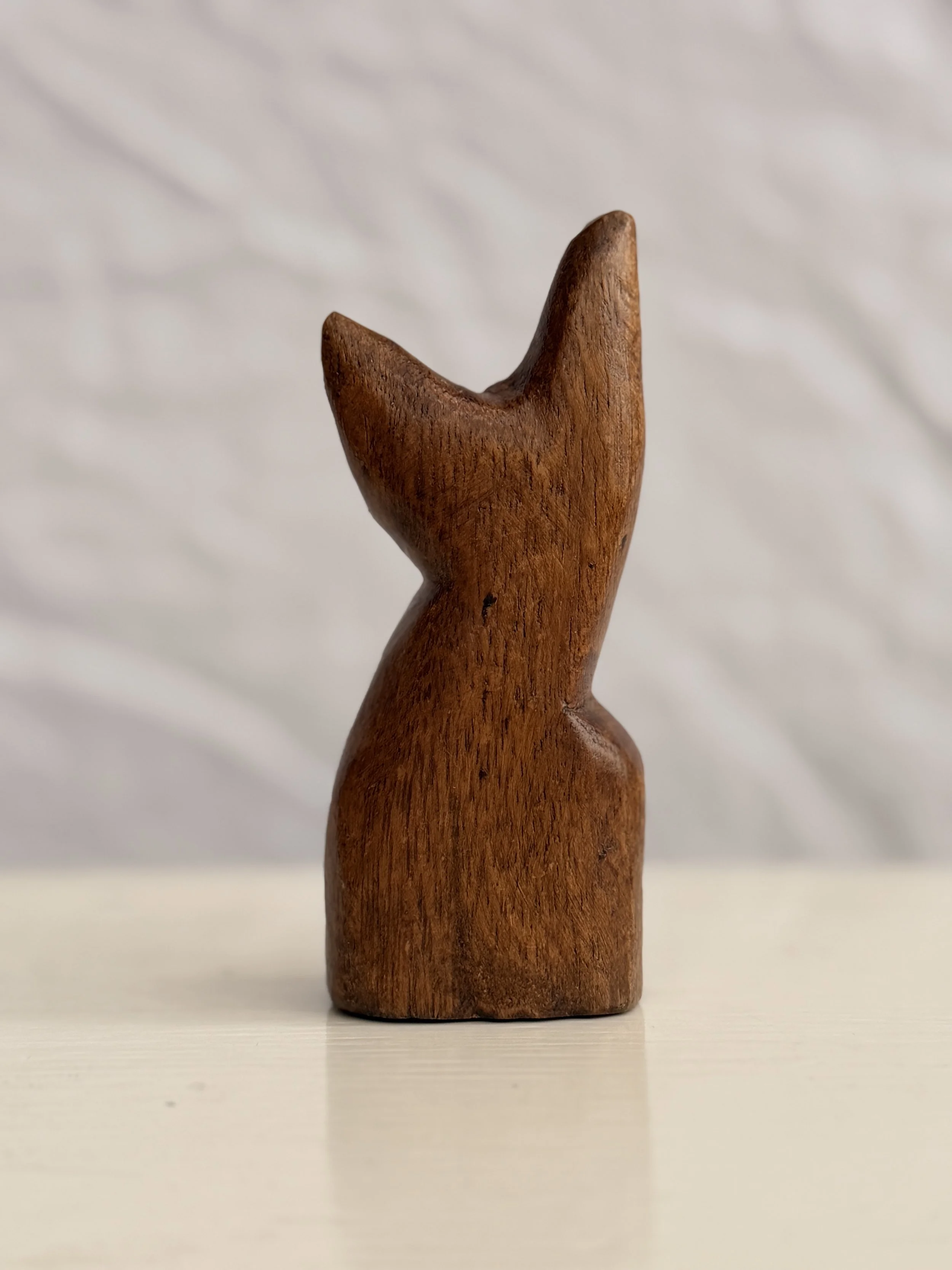 Back view of the wooden cat sculpture showing the continuous grain of the natural wood.