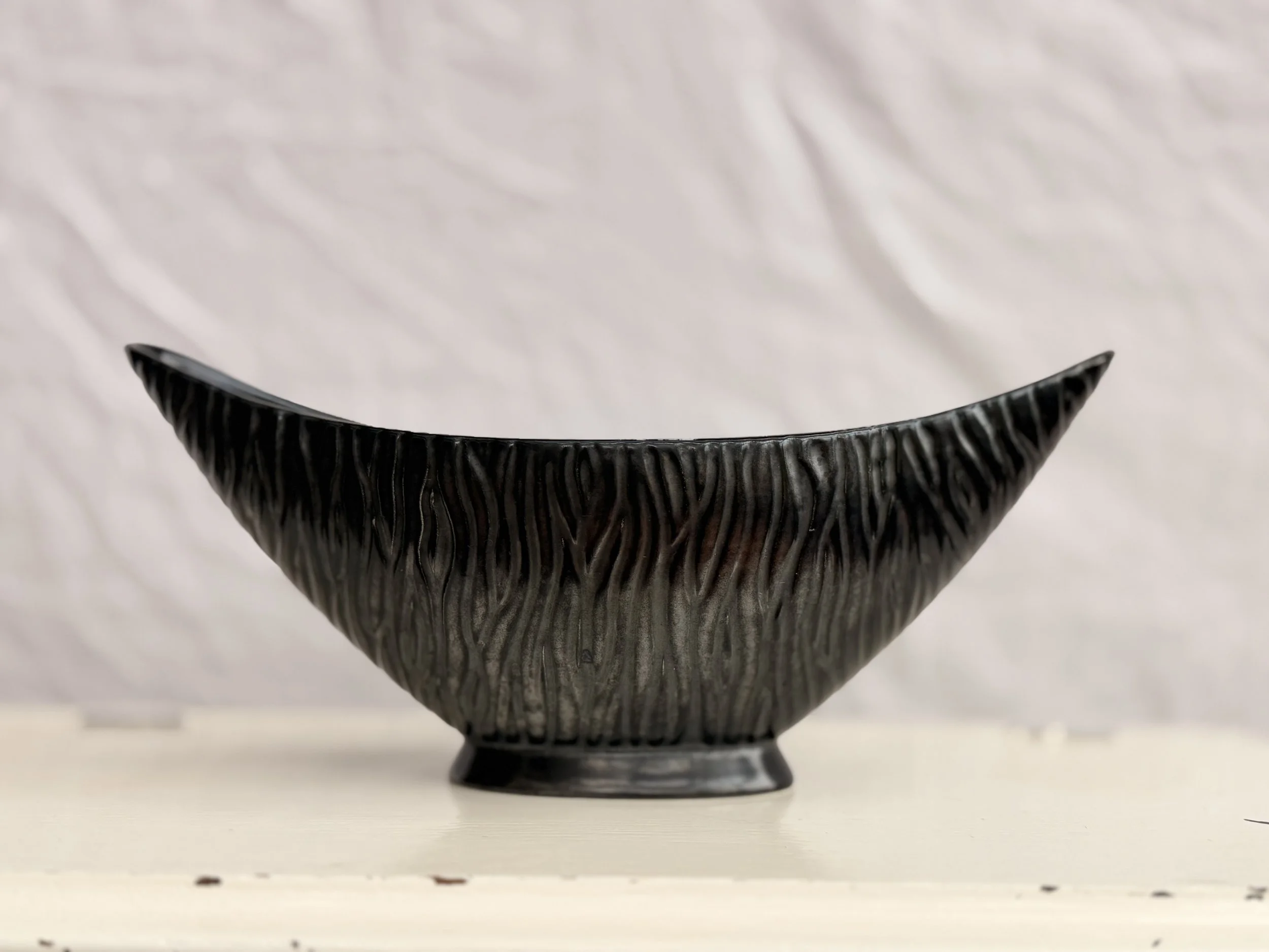 A large vintage black gondola mantle vase with a sleek, elongated boat shape.