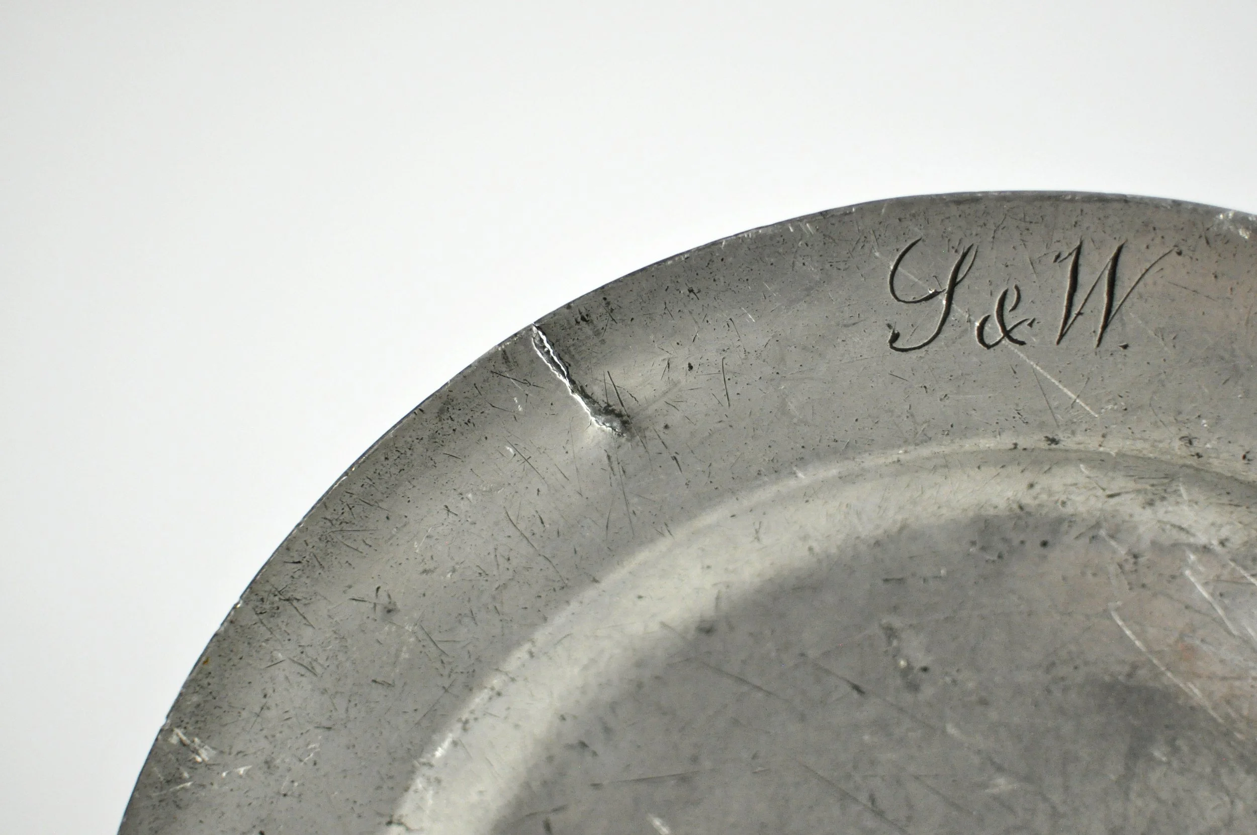 Close up of rustic aged patina and pseudo-hallmarks on antique English pewter.