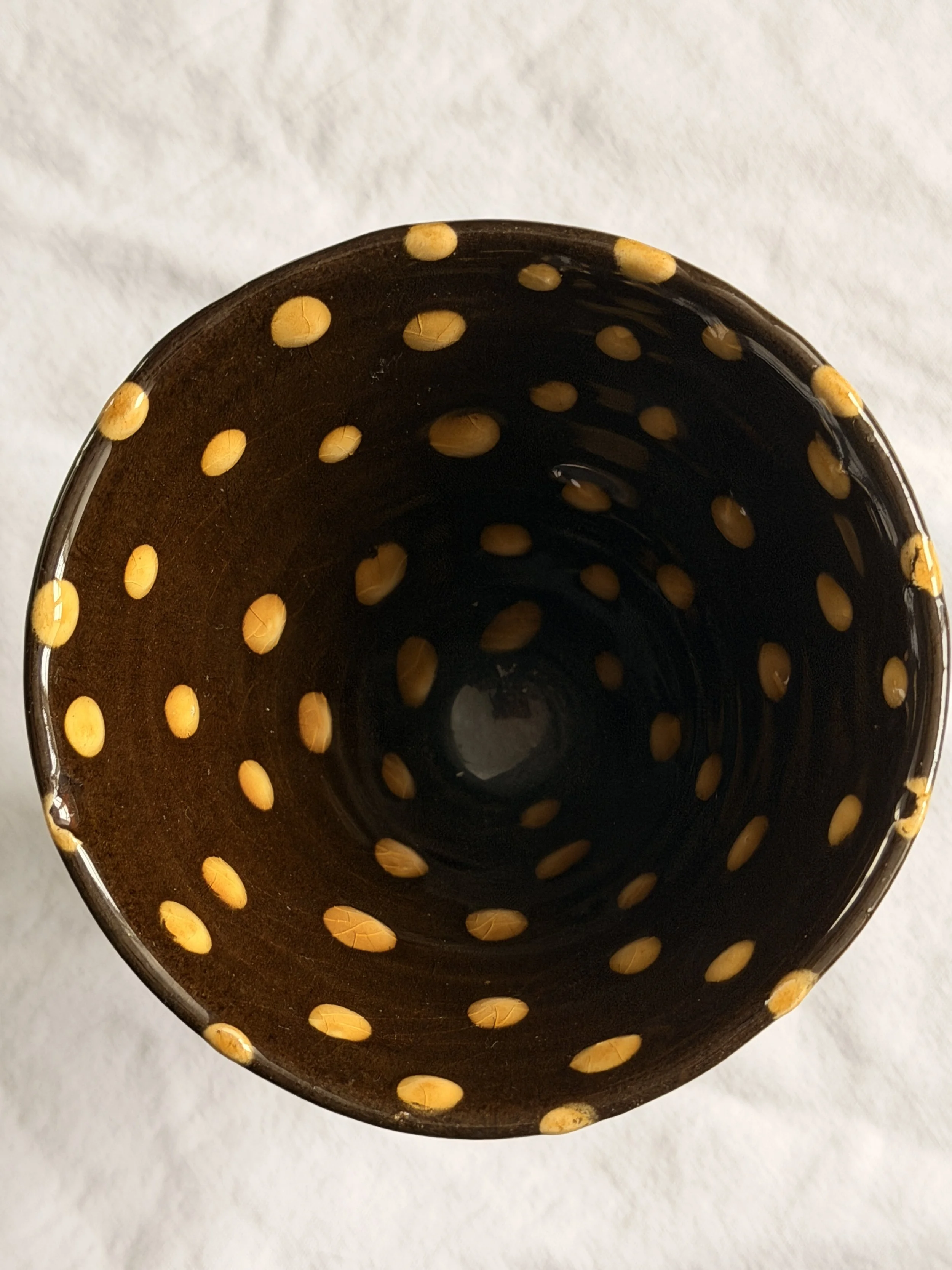 etailed view of the hand-applied polka dot slipware on a brown stoneware chalice.