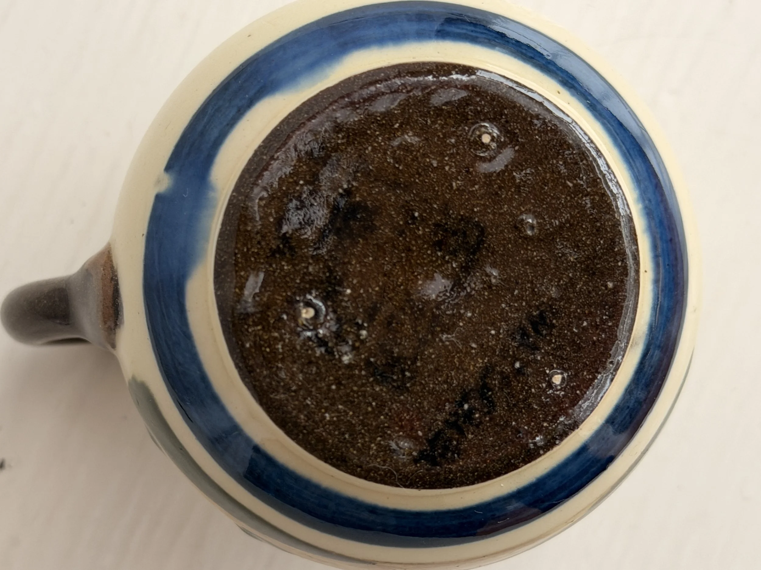 A small vintage Watcombe Pottery cream jug featuring a hand-painted English cottage scene and a traditional motto.