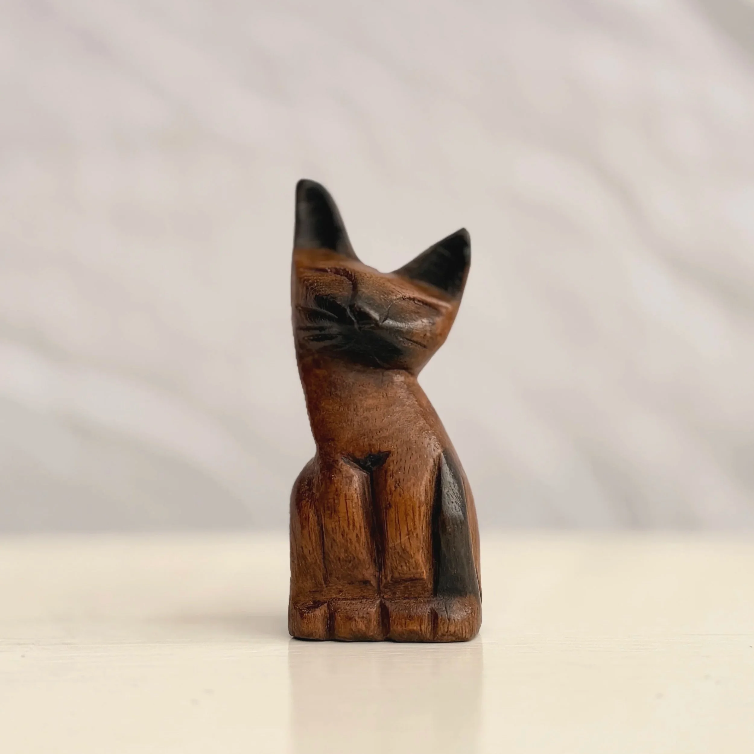 A hand-carved wooden cat figurine with a smooth, vintage-style finish and visible wood grain.
