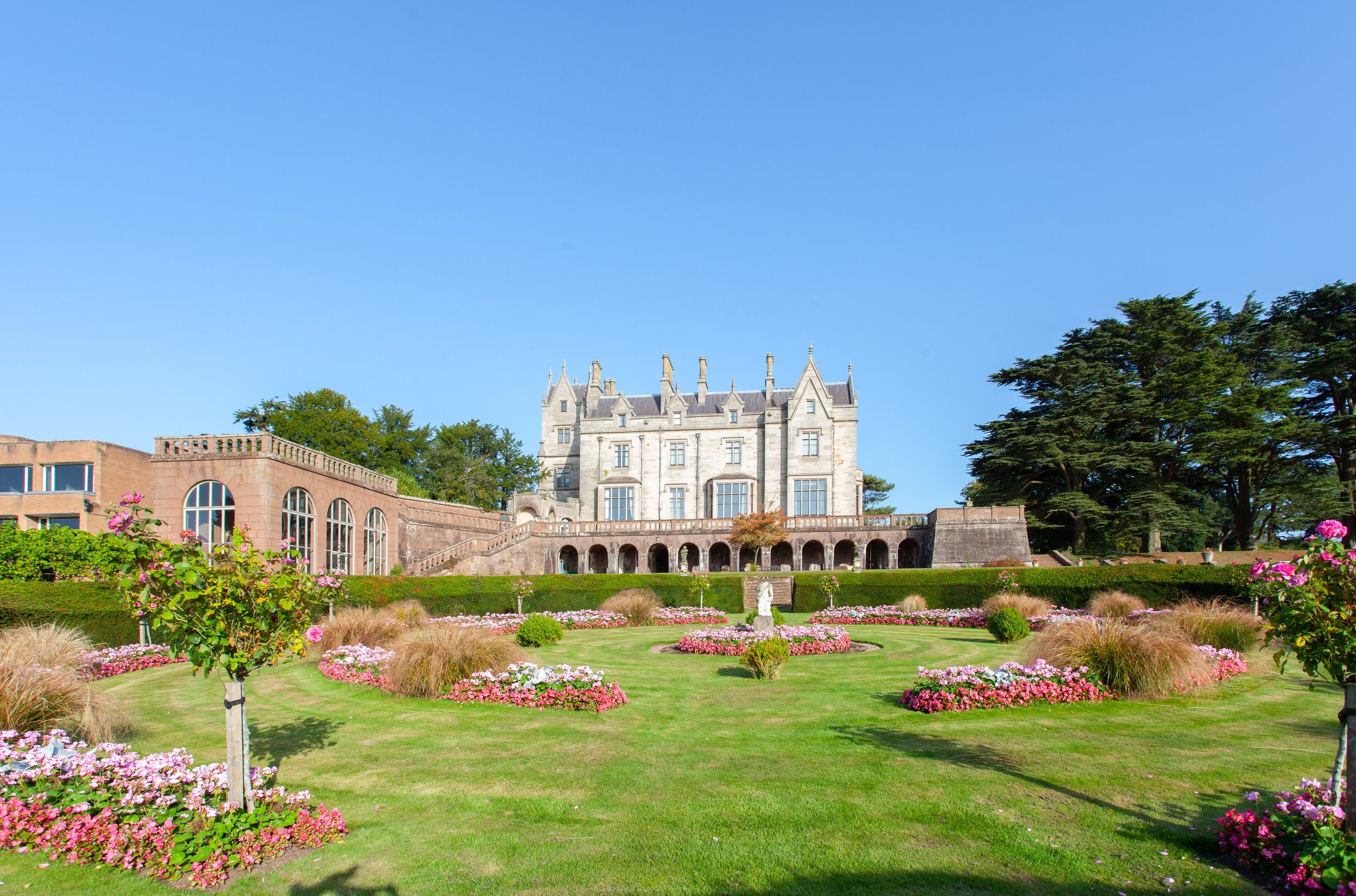 Historic mansion with gardens and lawn, clear blue sky