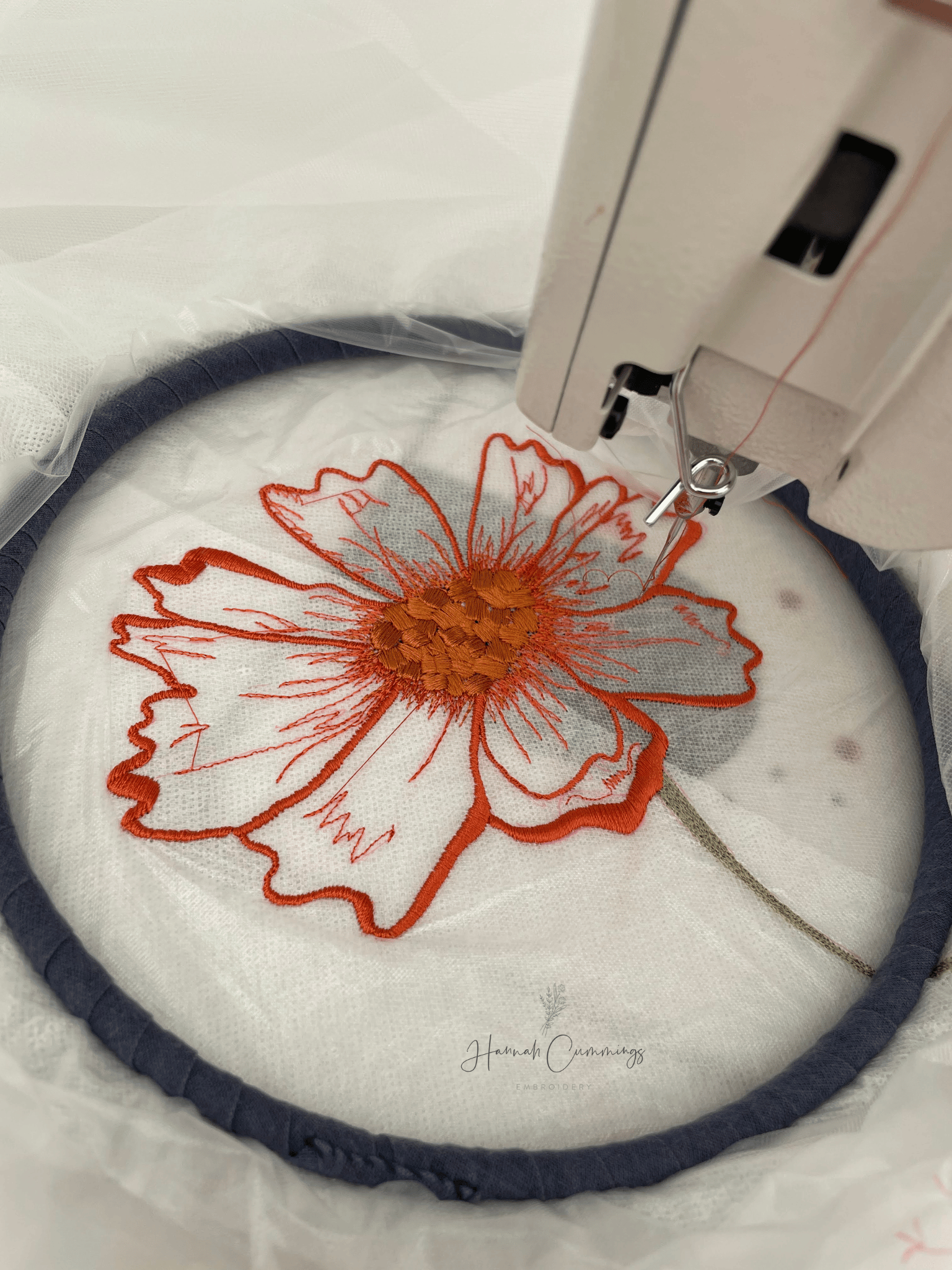  Orange flower being embroidered at sewing machine 