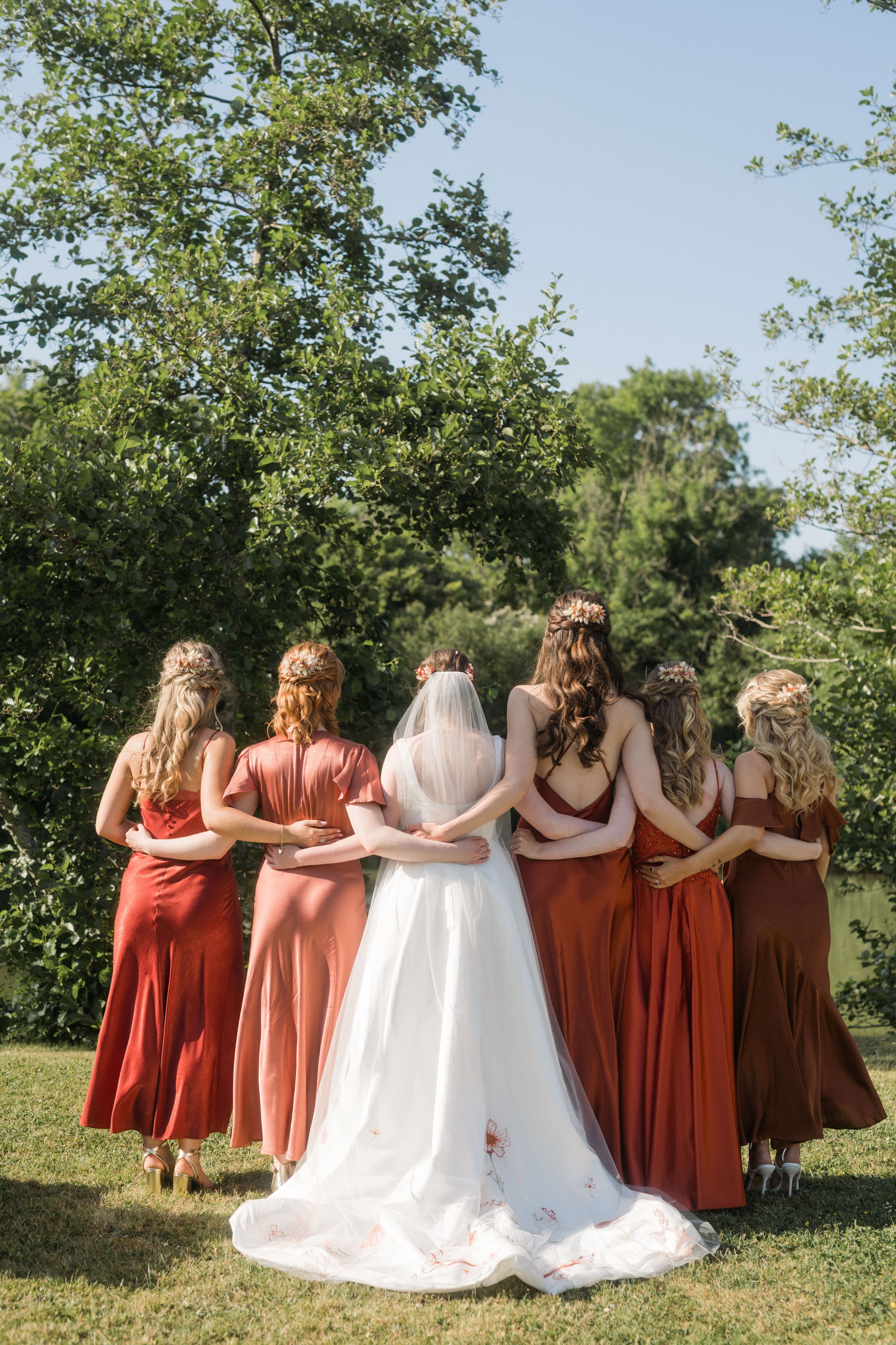  Bride with her bridesmaids facing away showing back of dresses and veil 