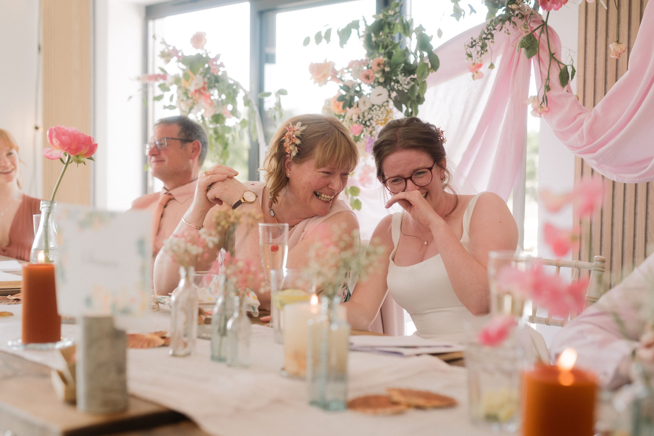 Bride and mother of bride laughing at top table