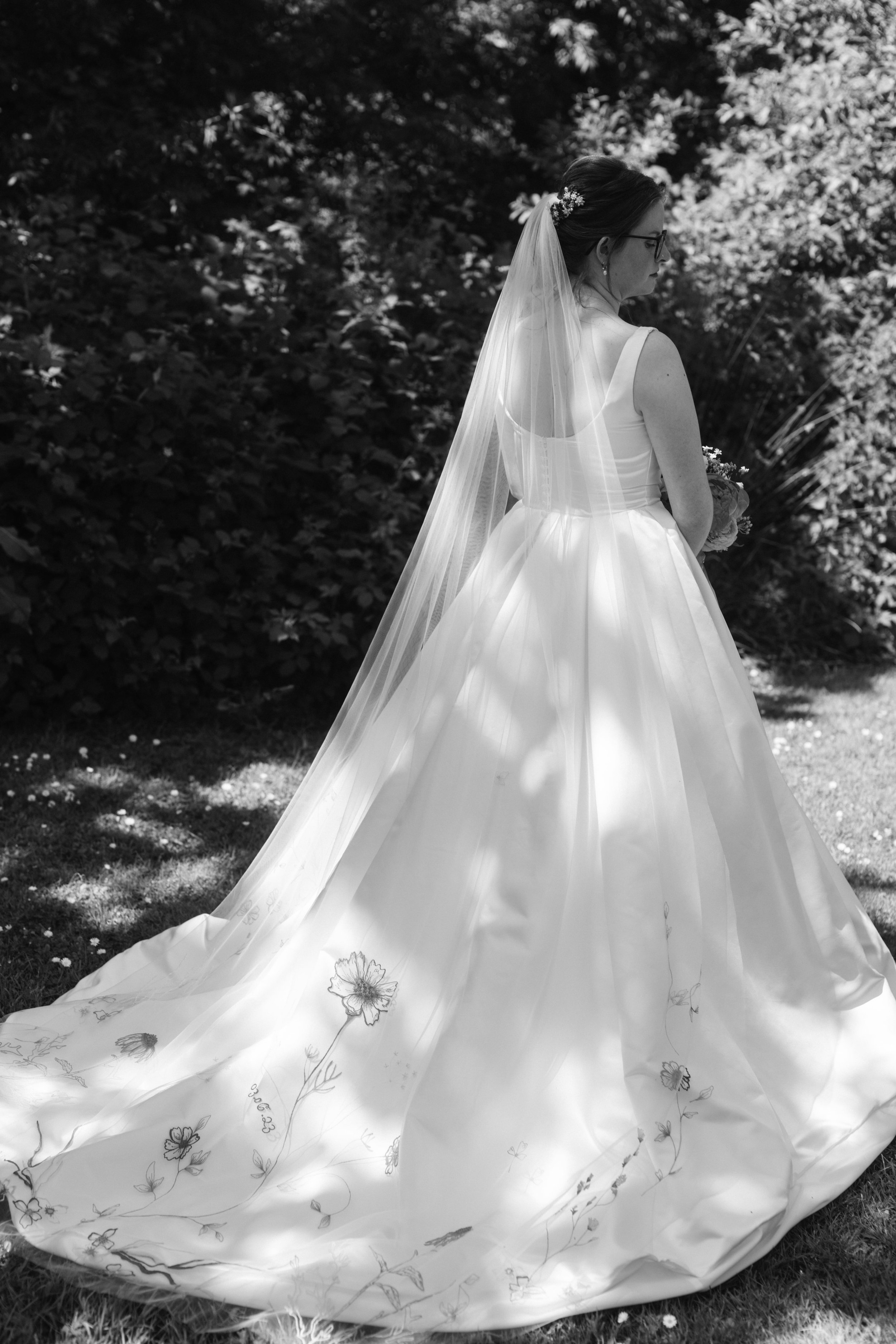  Black and white image of bride facing away wearing embroidered veil 