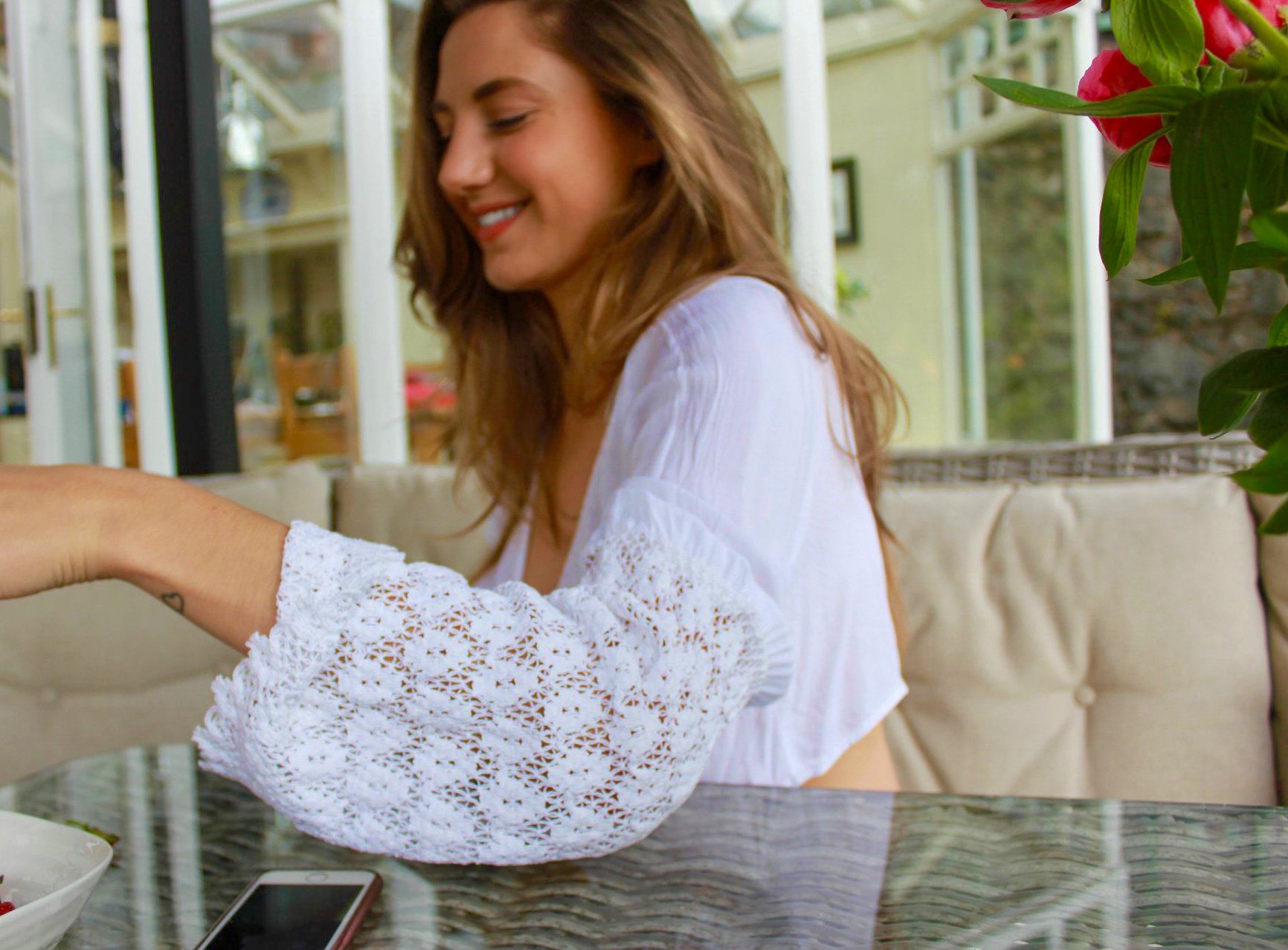 Amy Follows smiling, wearing a white top with crocheted sleeves