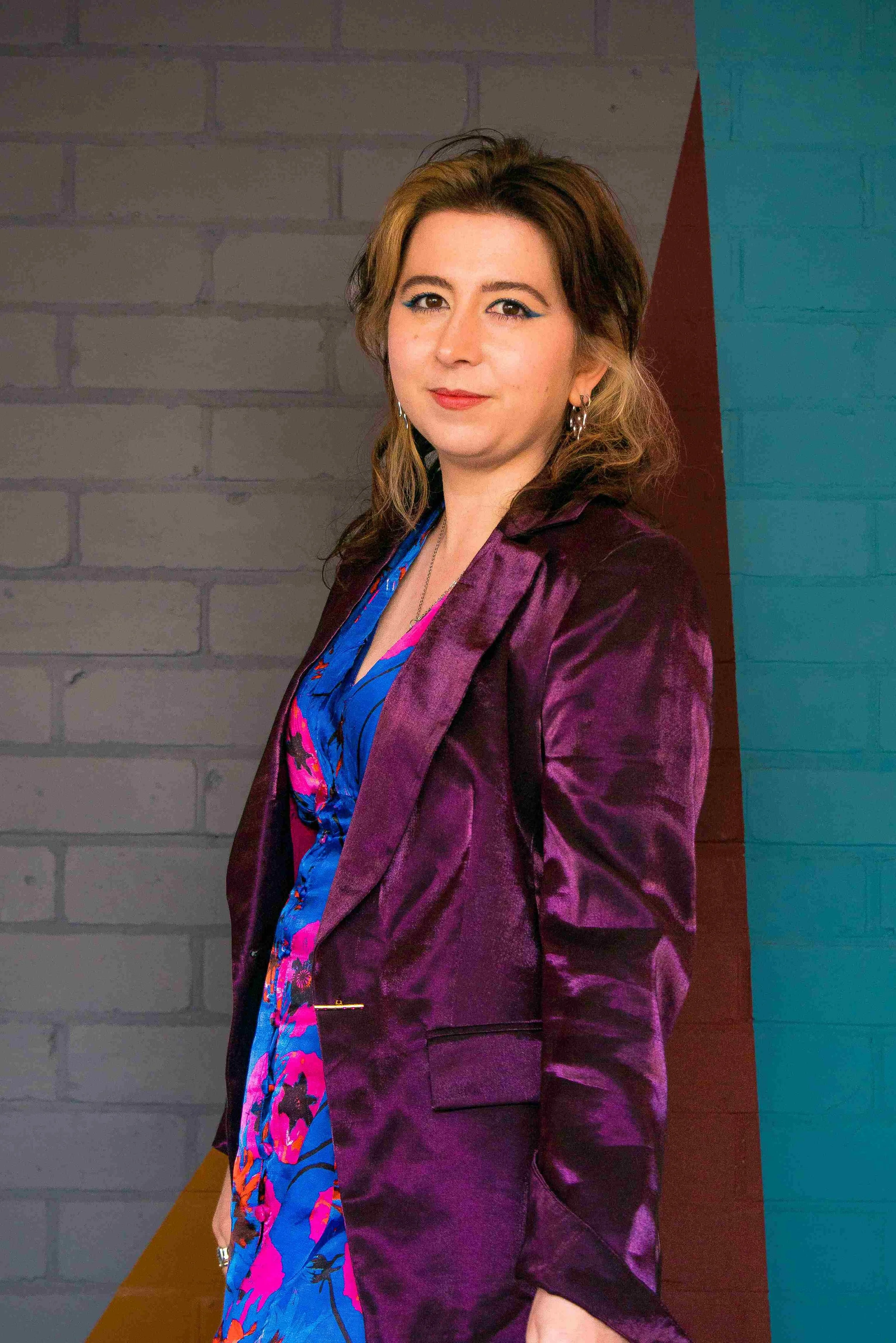 A photo of Ebony-Storm, Norwich copywriter, standing to the side in a purple and blue outfit