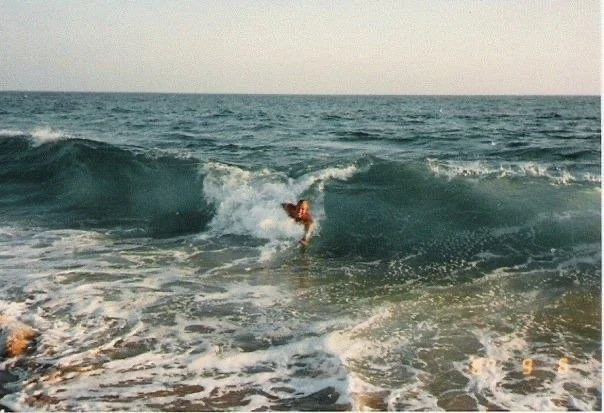 A person is surfing in the ocean on a wave near the shore.