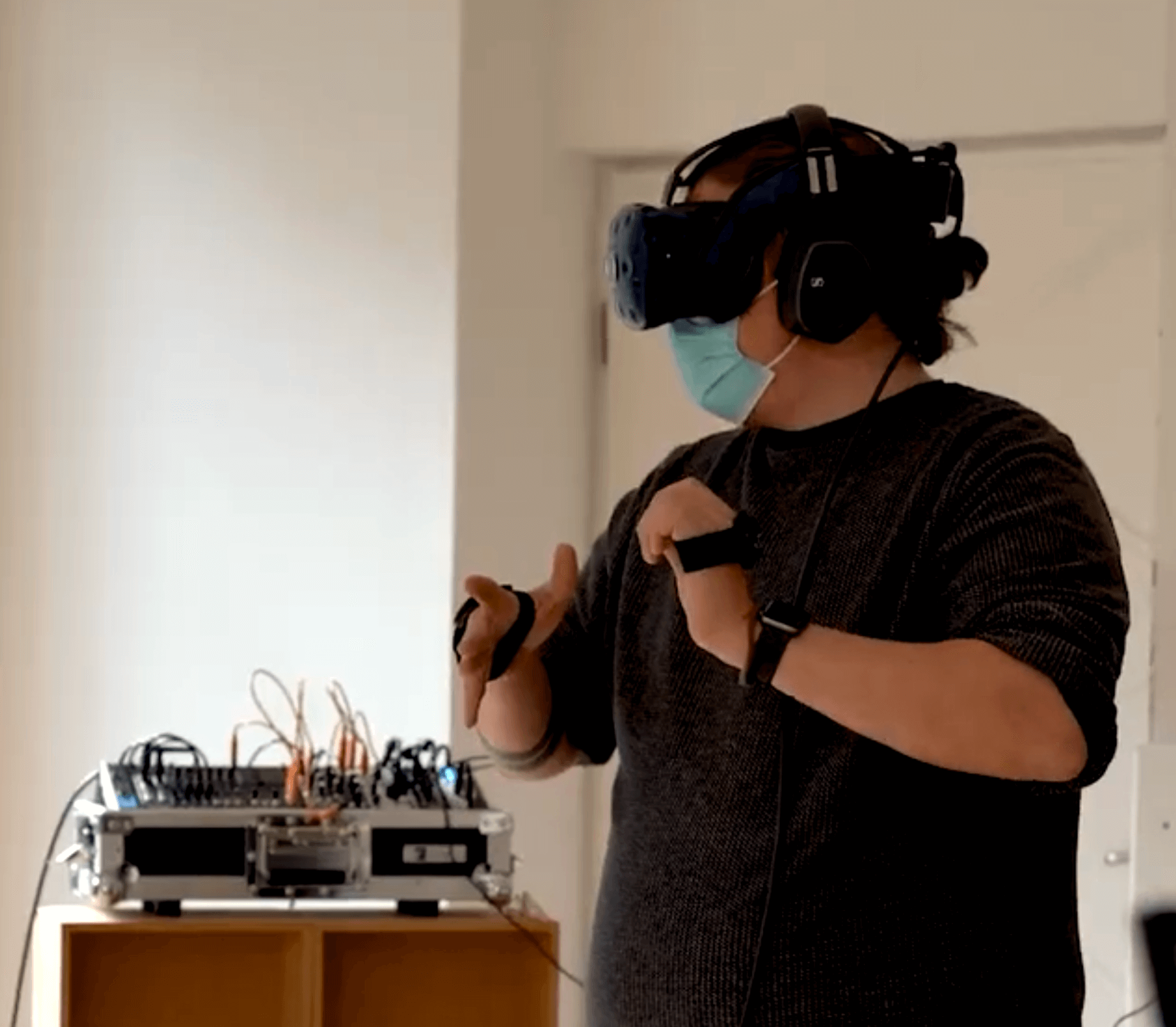 Image showing Steffen Müller using his virtual reality installation in which handheld sensors control a modular synthesiser that is generating sounds. these sounds are interpreted by the software tounchdesigner as animated images that get send to VR