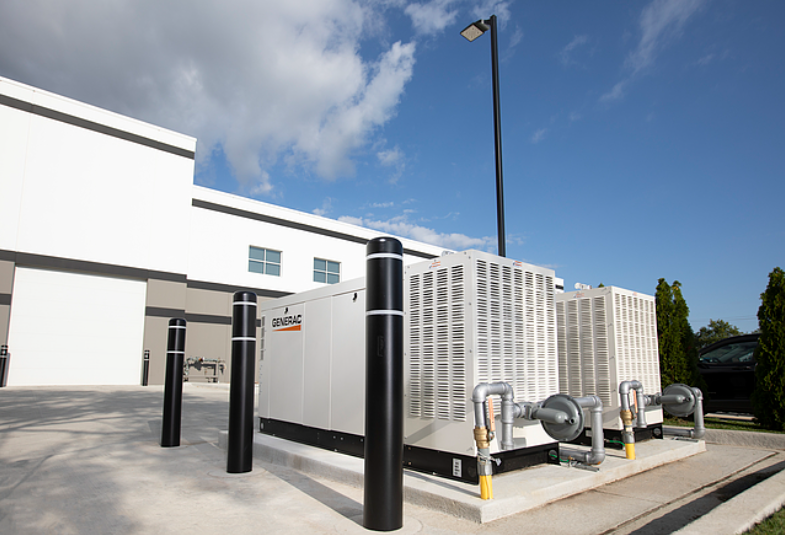 Commercial sized Generac generator in rear parking lot of business.