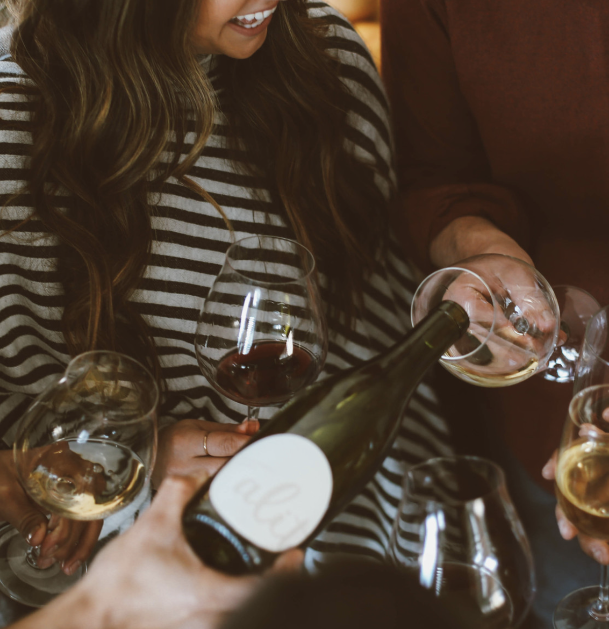 People pouring and drinking wine at a social gathering.