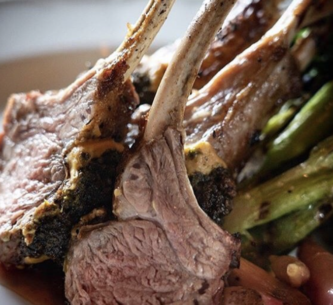 Close-up of cooked lamb chops with a side of green vegetables.