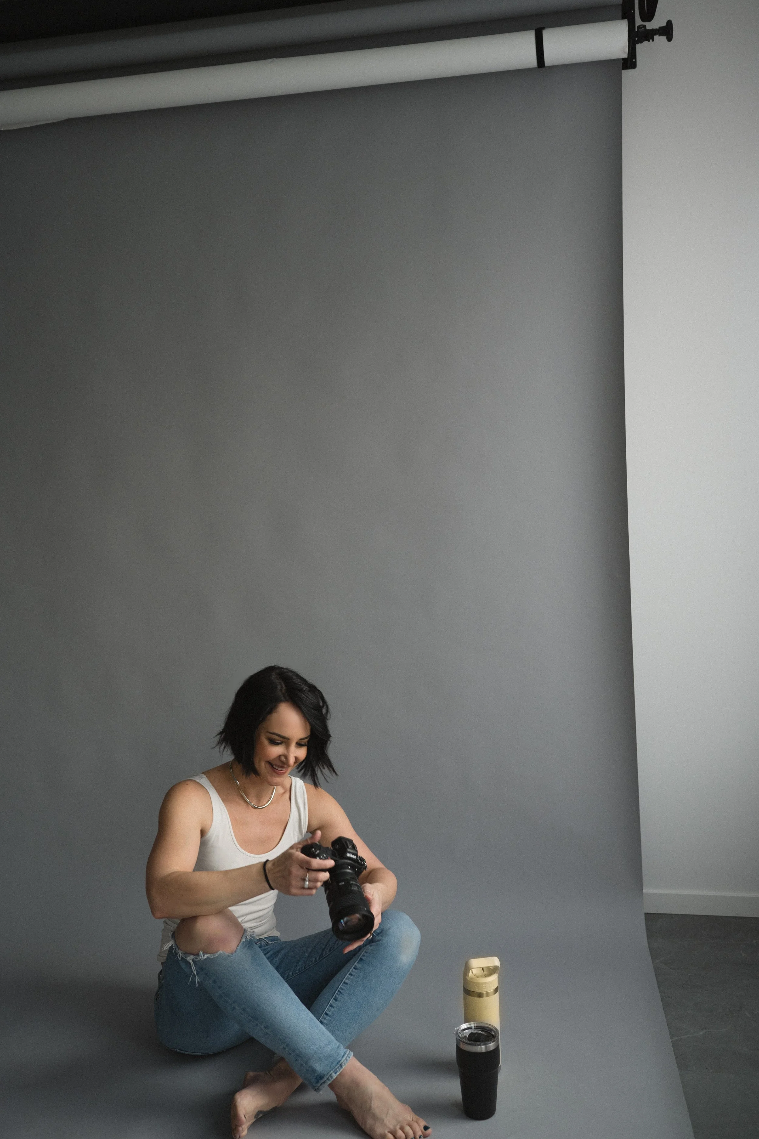 woman holding camera on studio backdrop