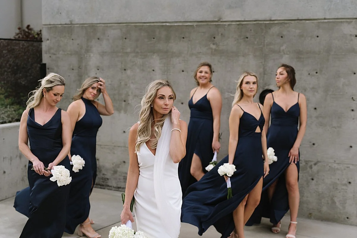 Bridesmaids looking super stylish against a concrete wall at Monte Creek Winery